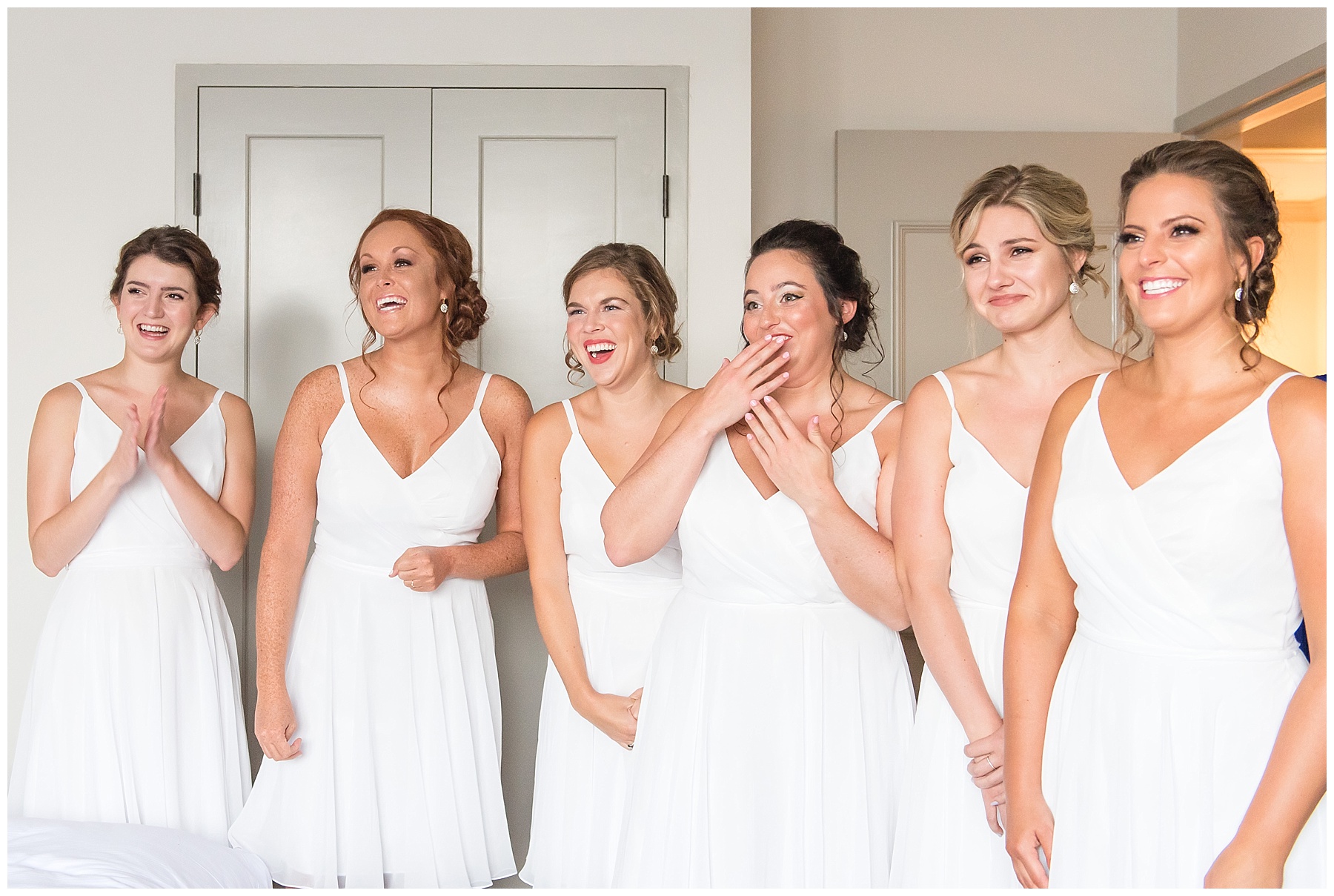 Bridesmaids in white dresses laughing and crying as they see bride for the first time in the 2018 wedding photography favorites