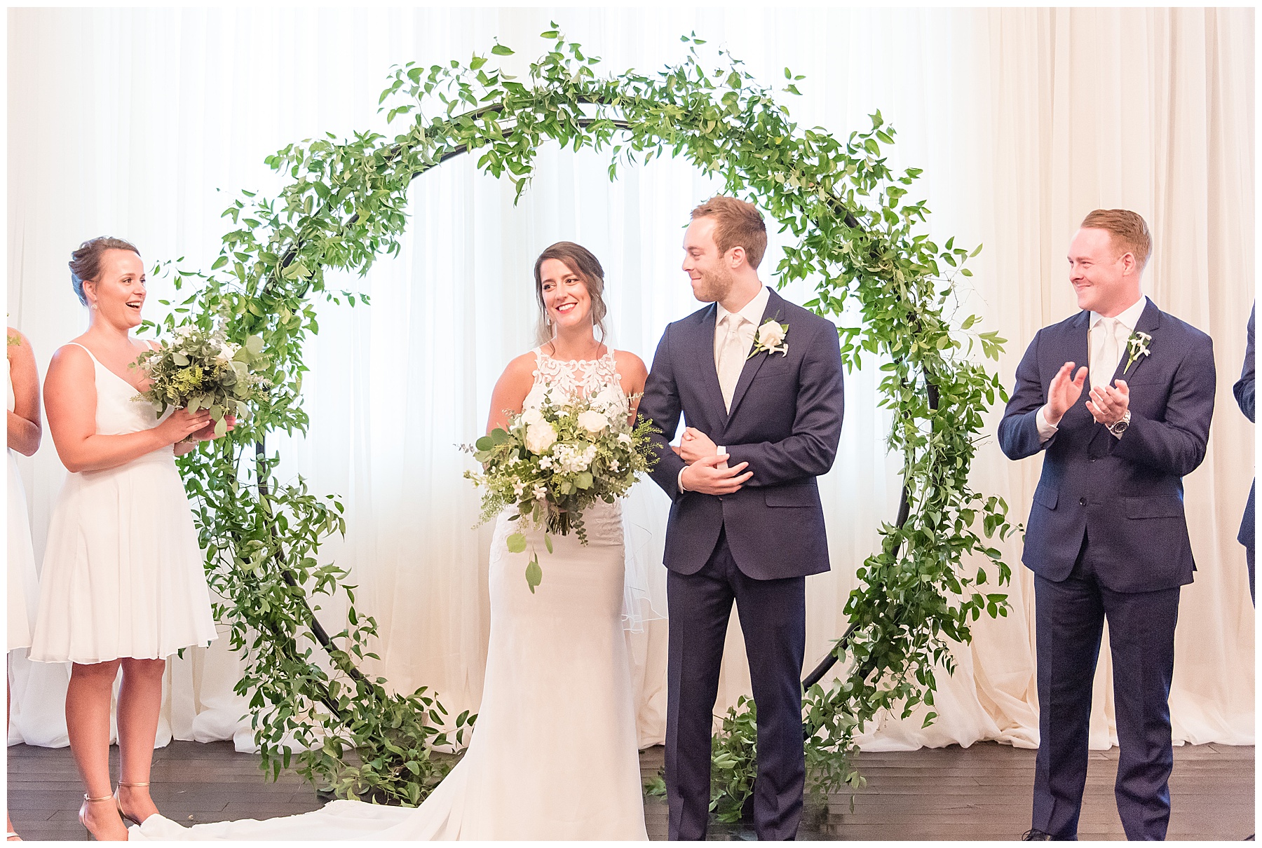 Bride and groom smiling at guests after sharing first kiss under floral hoop in my wedding photography favorites
