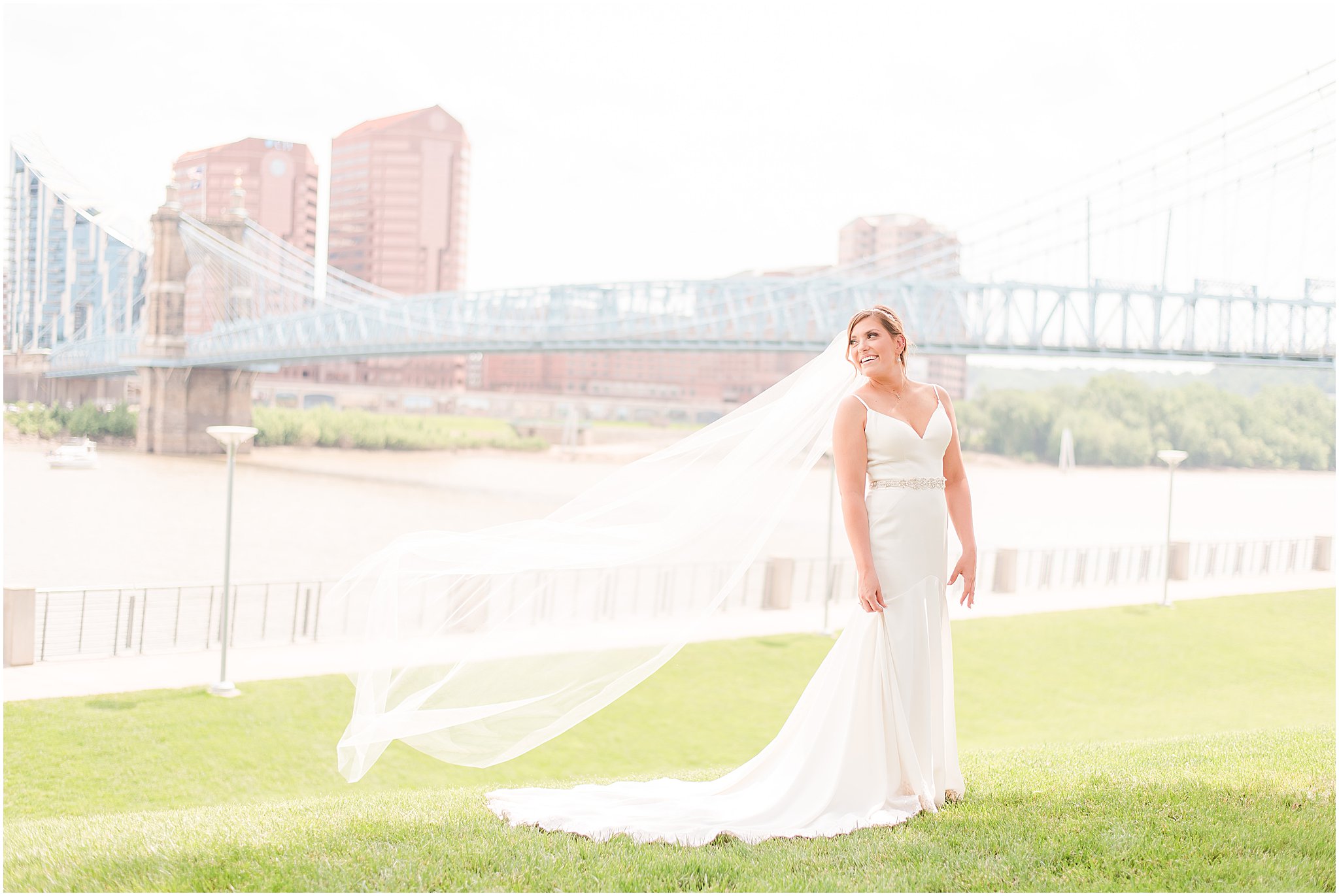 Bride standing in front of a bridge with her veil blowing in the window during her wedding at The Phoenix Cincinnati