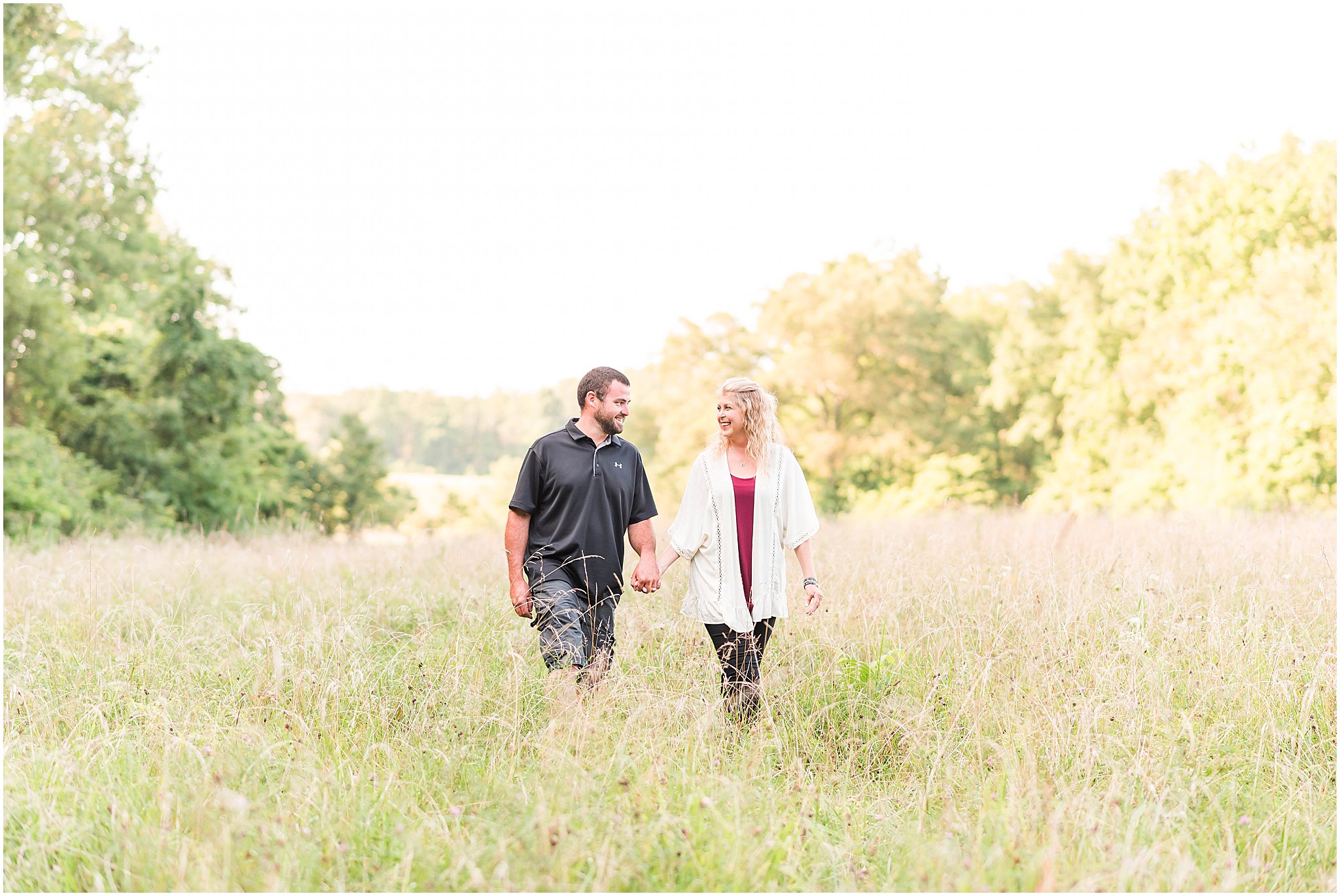 Bloomfield Indiana engagement session guy and girl walking through field at sunset