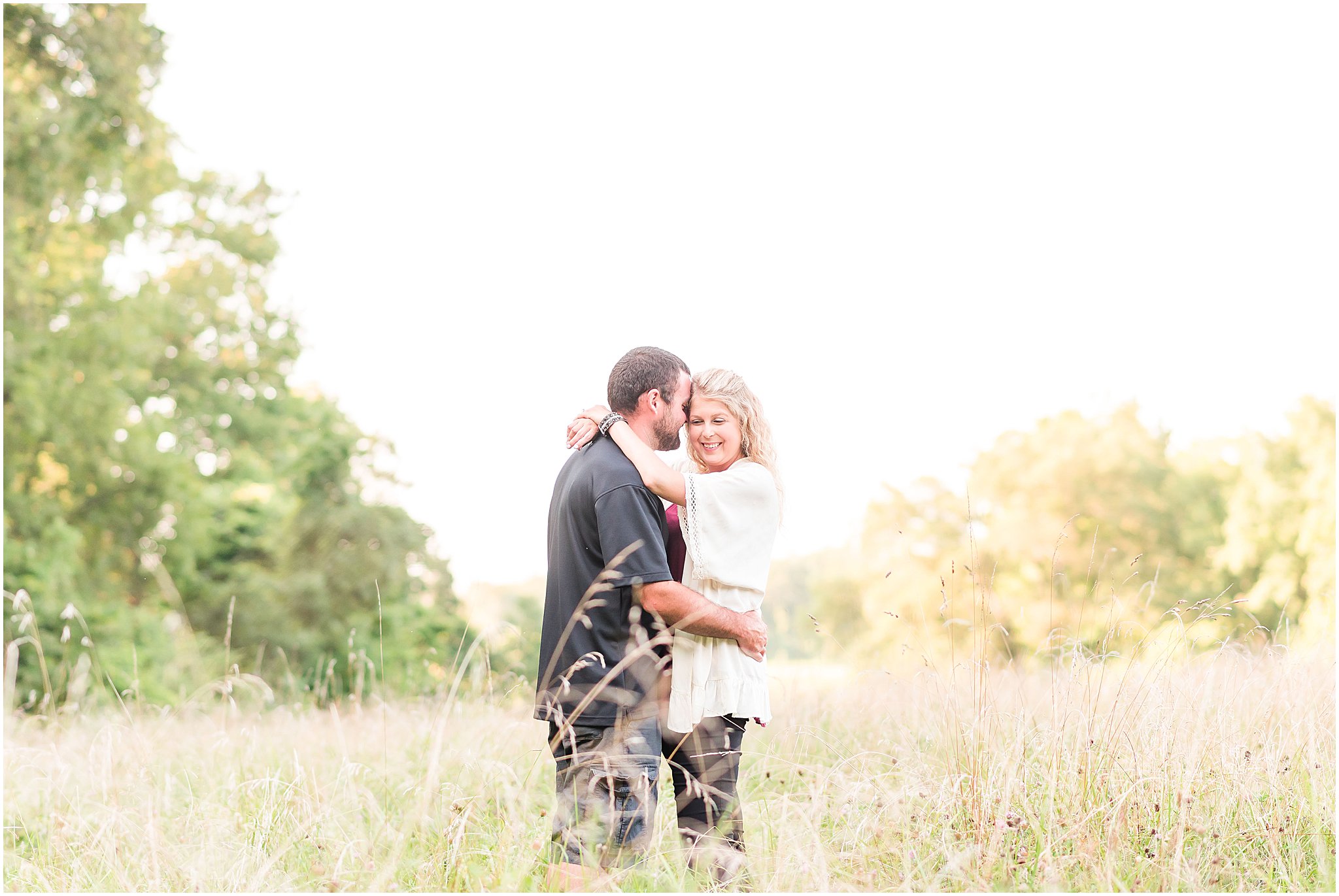 Bloomfield Indiana engagement session with guy nuzzling girl's temple while standing in field