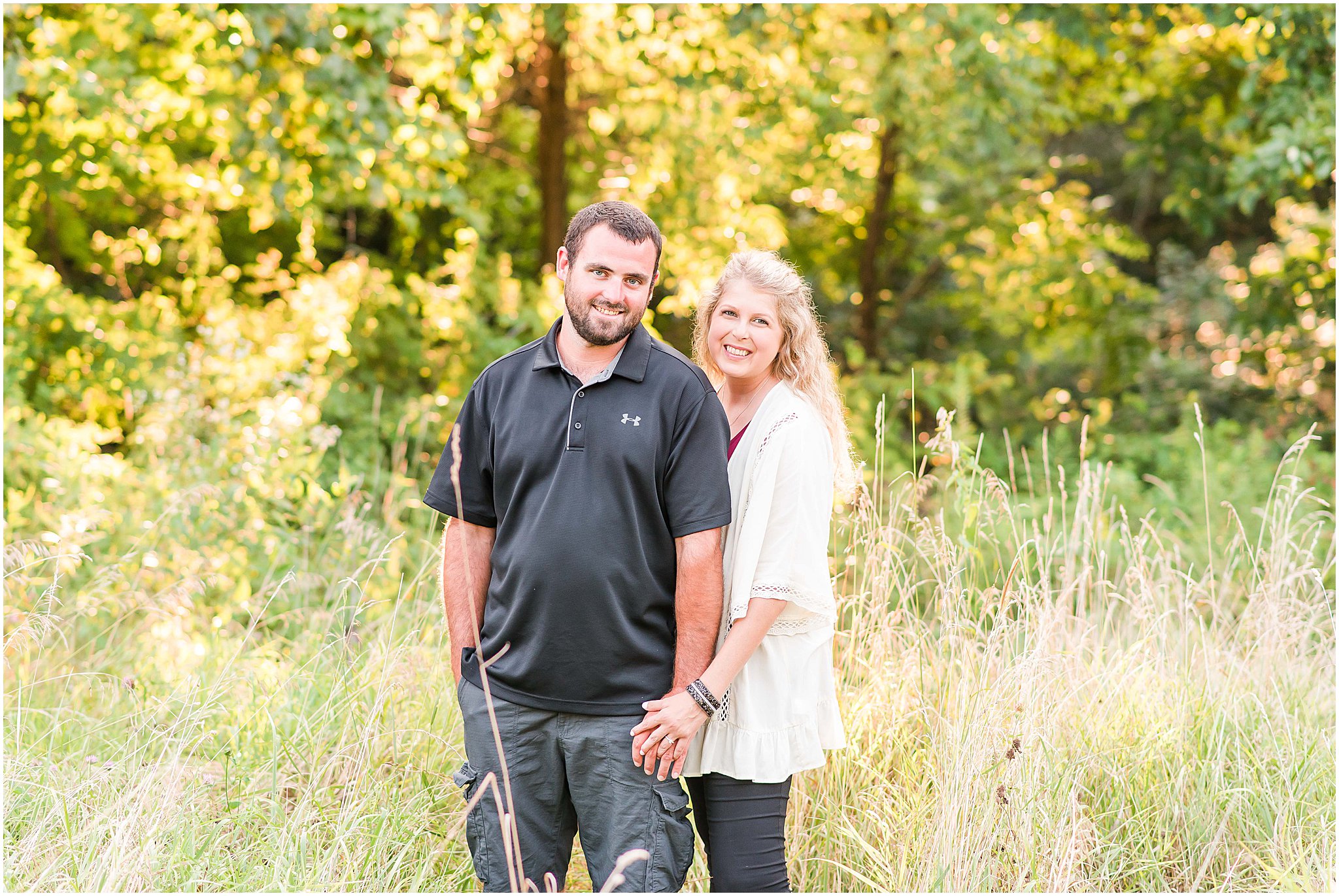 Bloomfield Indiana engagement session couple smiling while standing in field at sunset
