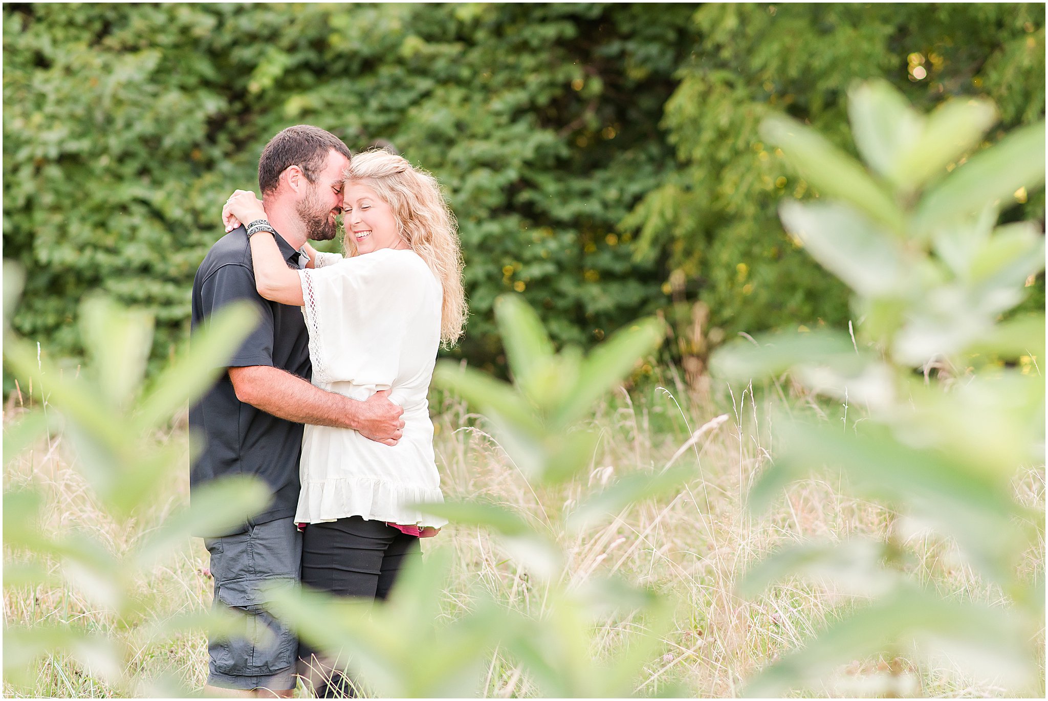 Bloomfield Indiana engagement session guy and girl standing in field, girl smiling over her shoulder