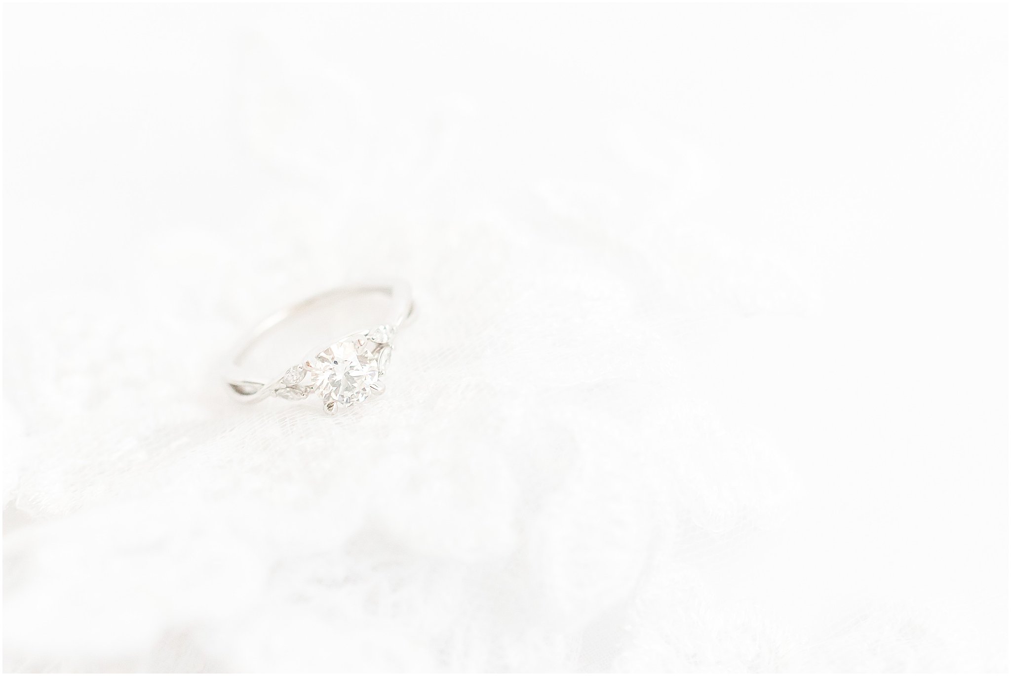 Round cut engagement ring laying on wedding veil lace at The Hawthorns Golf and Country Club