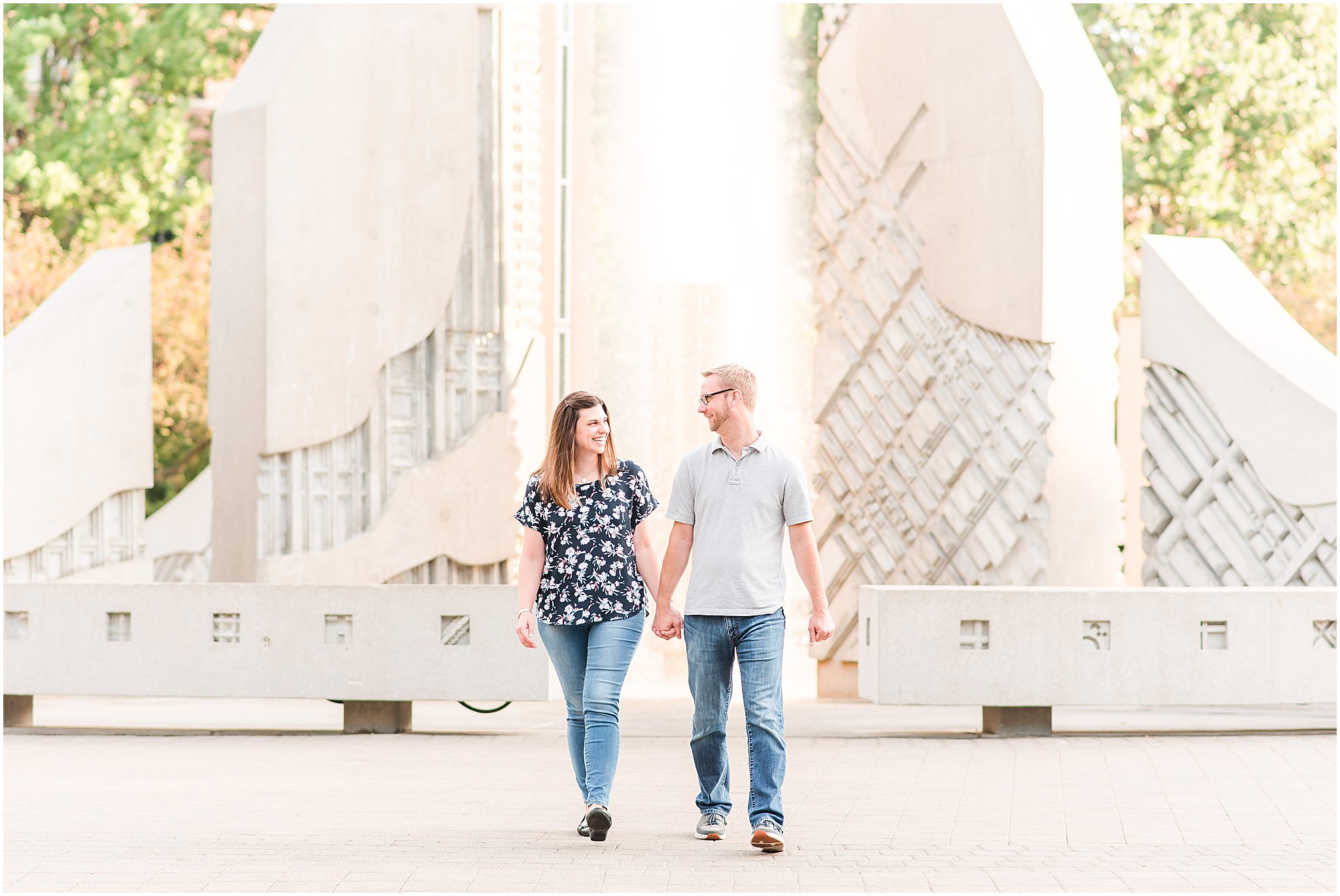 Couple holding hands and walking in front of the engineering fountain at Purdue University