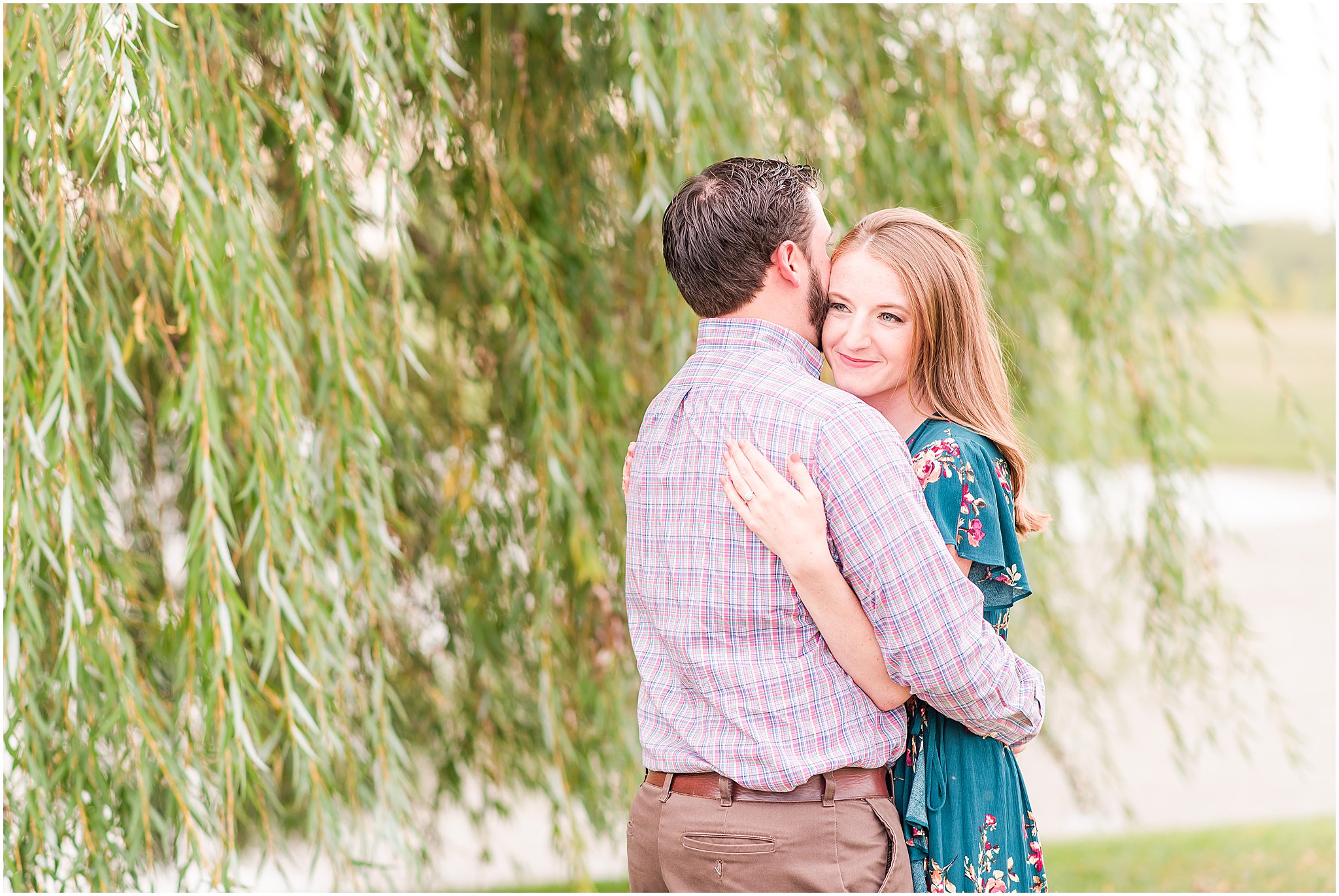 Bride and groom nuzzling in front of willow tree during Coxhall Gardens engagement session