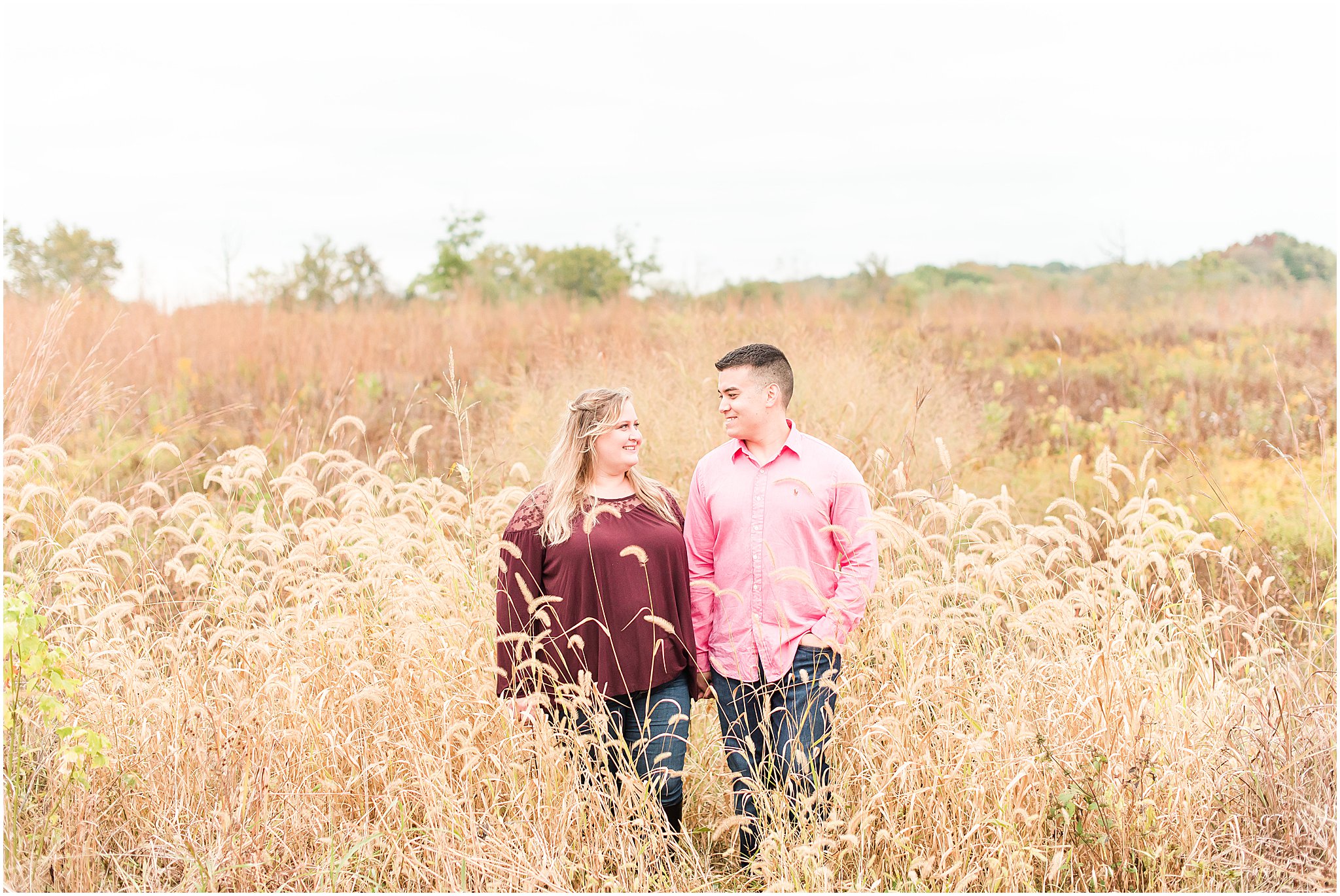 Couple holding hands and walking through field during Beckley Creek Park engagement session