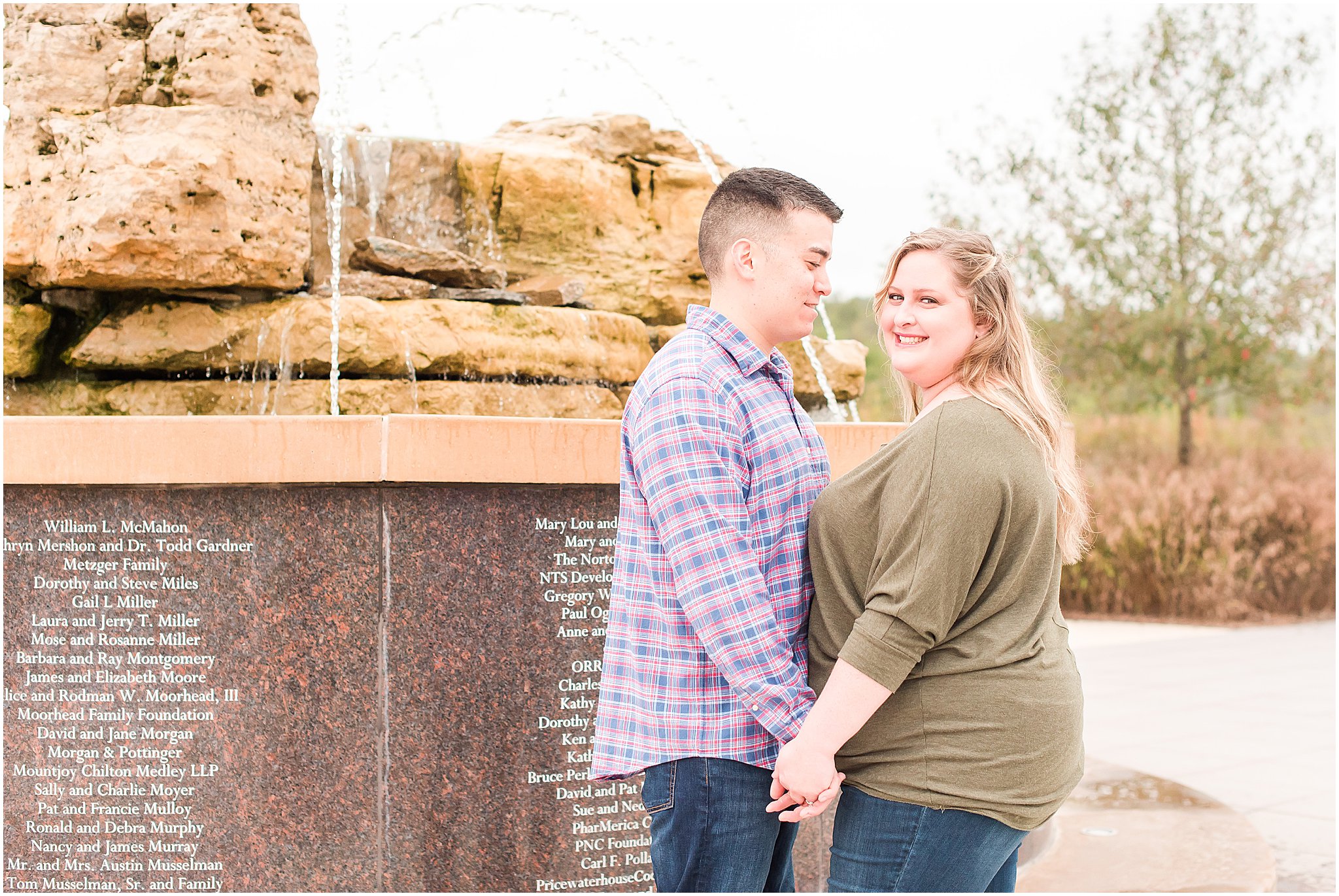 Couple holding hands in front of fountain during Beckley Creek Park engagement session