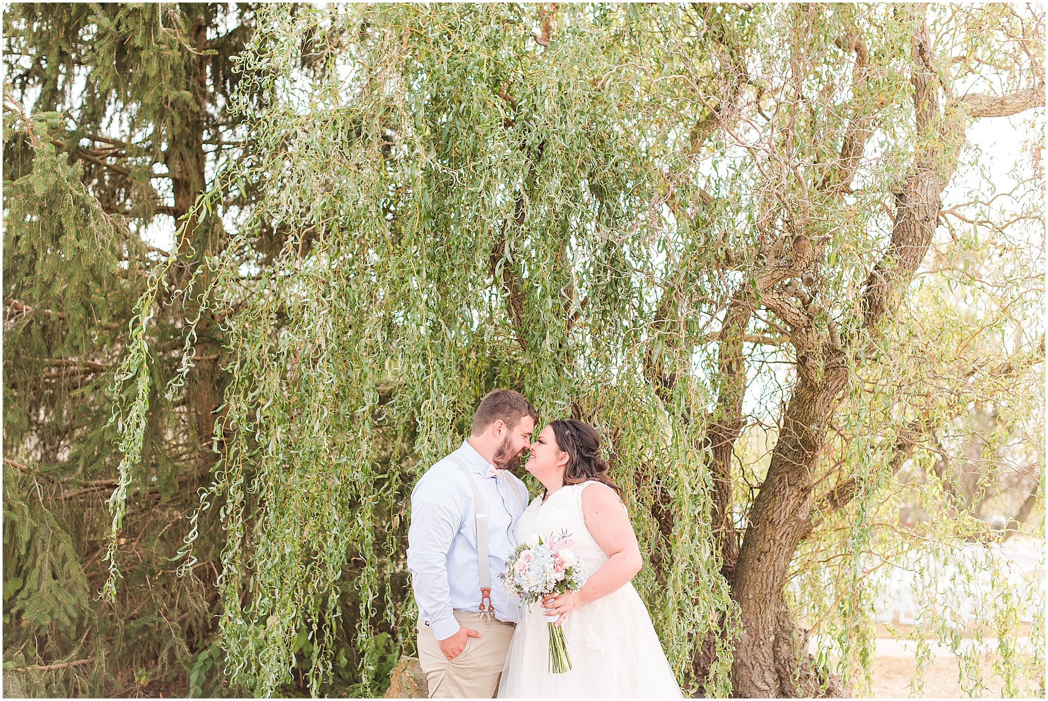Bride and groom nose to nose in front of willow tree at Cornerstone Hall in Salem, IN