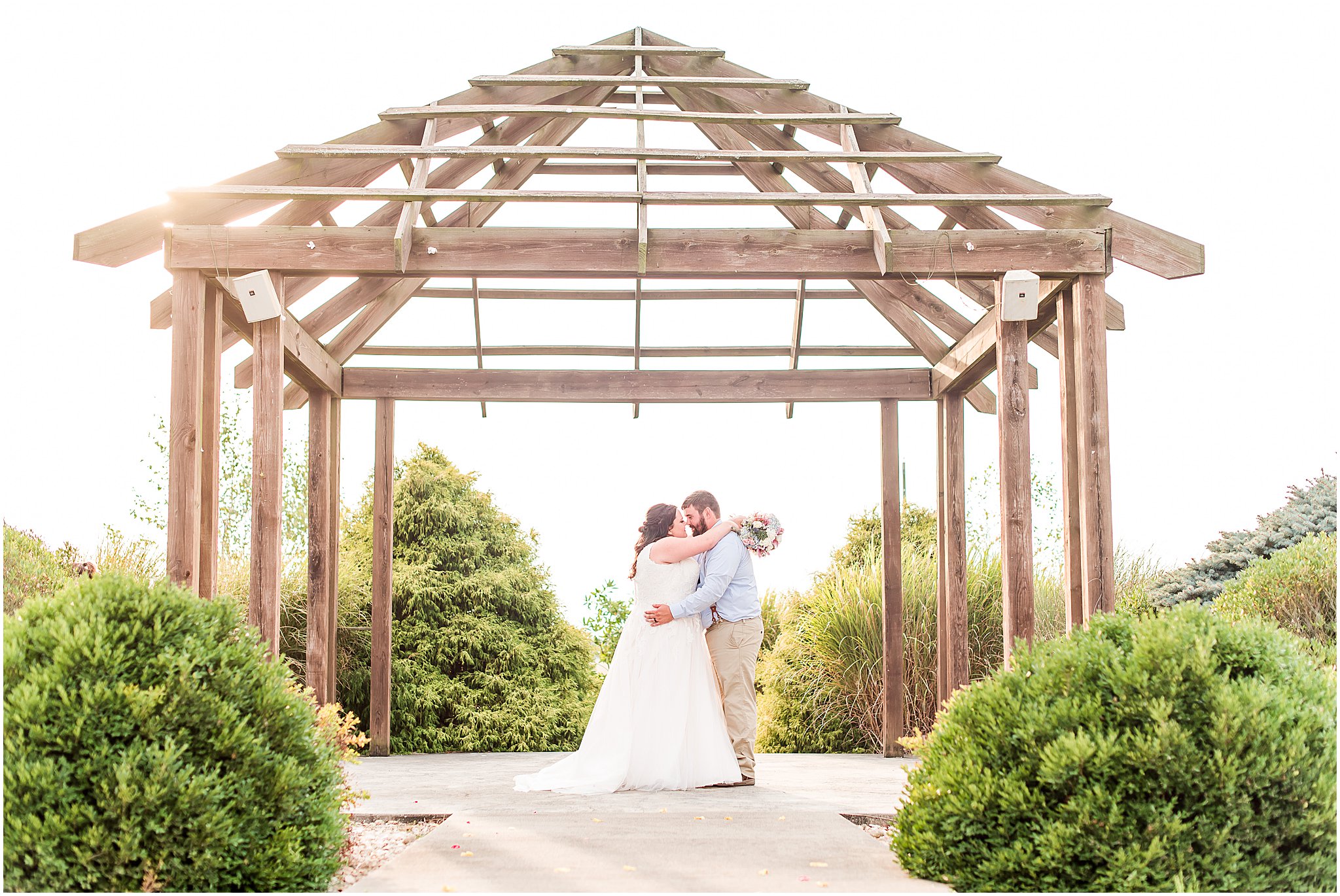 Bride and groom nose to nose under arbor at Cornerstone Hall in Salem, IN