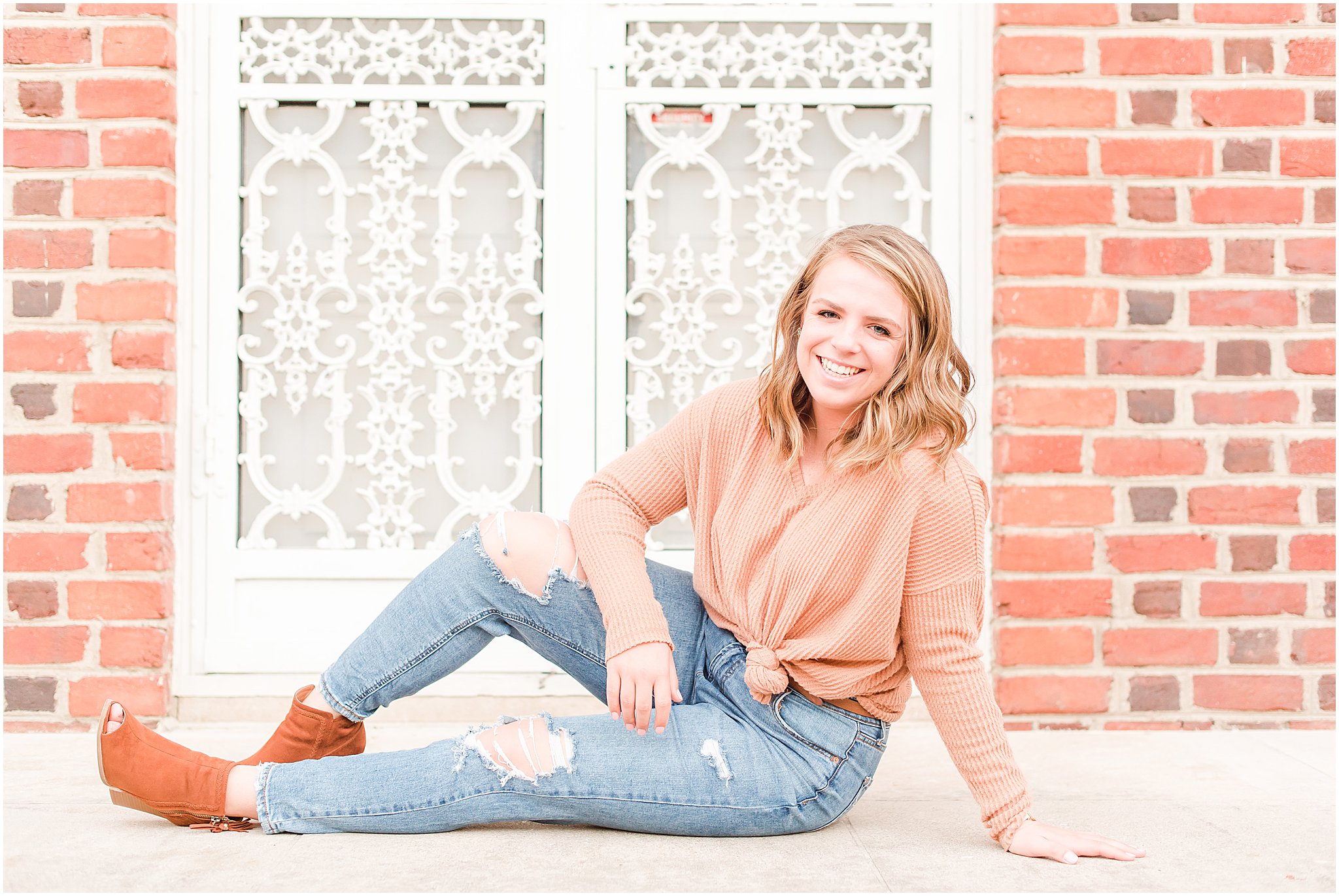 Girl sitting and laughing at camera during Coxhall Gardens senior session