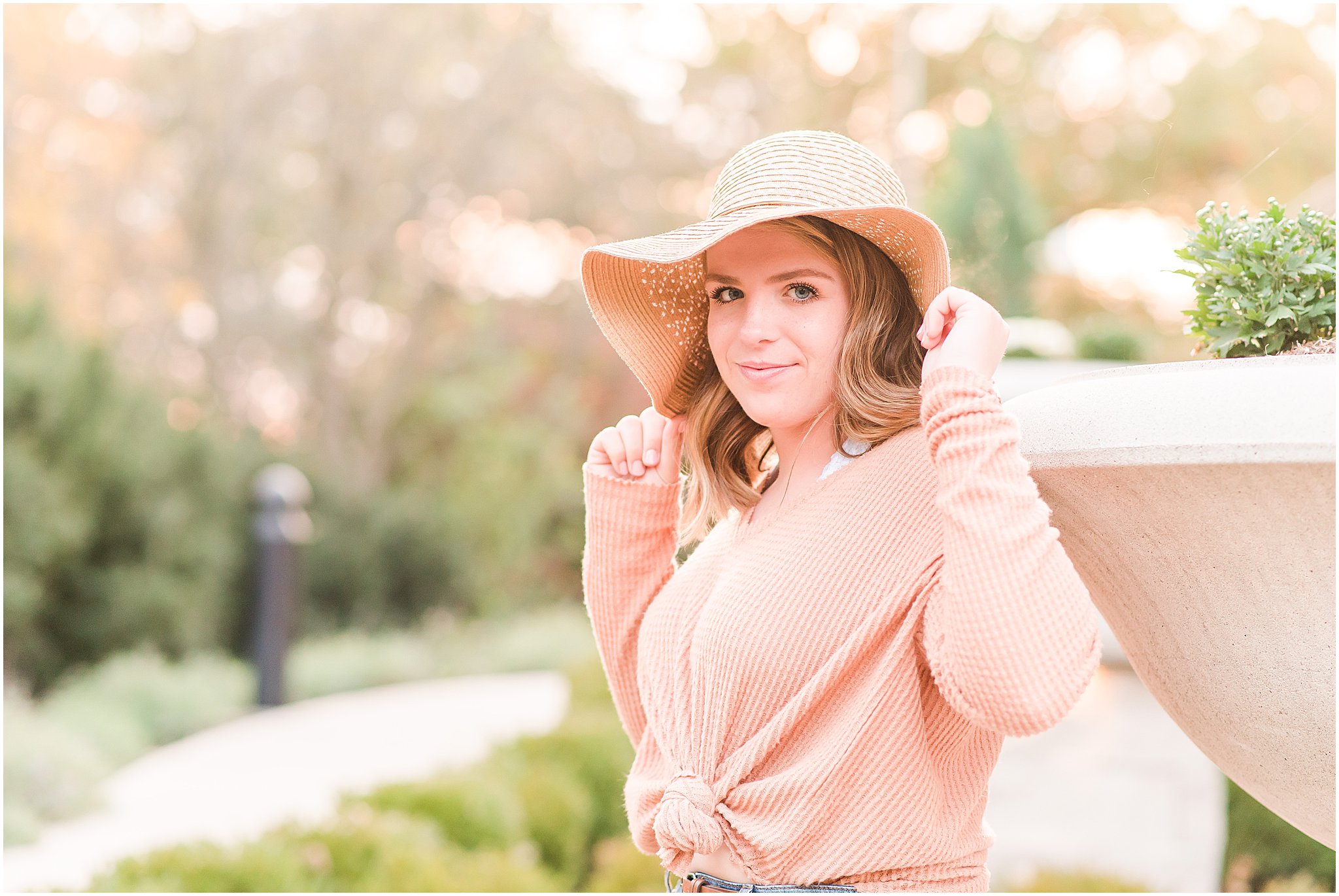 Girl smiling at camera in floppy tan hat during Coxhall Gardens senior session