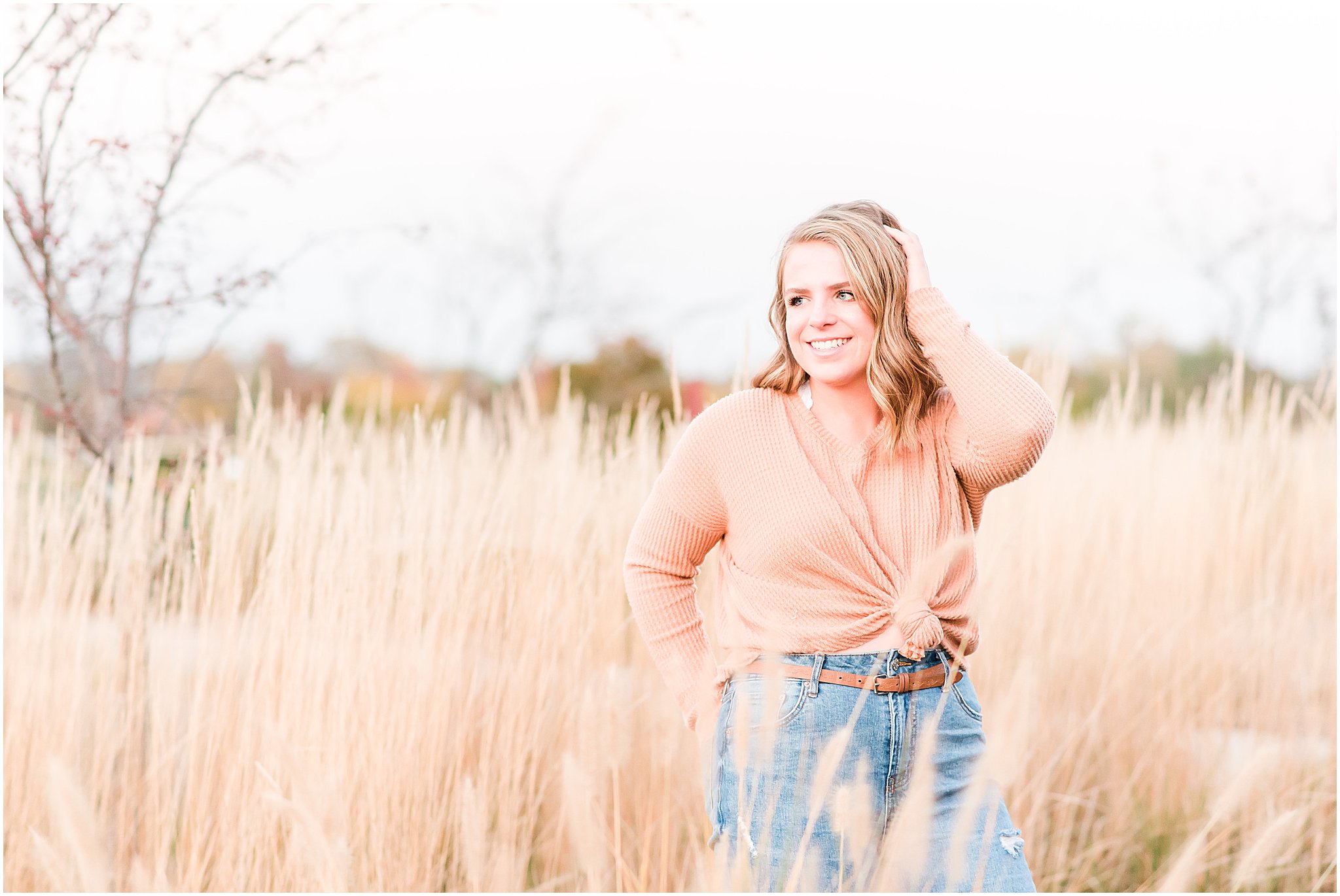 Girl in field smiling off camera during Coxhall Gardens senior session