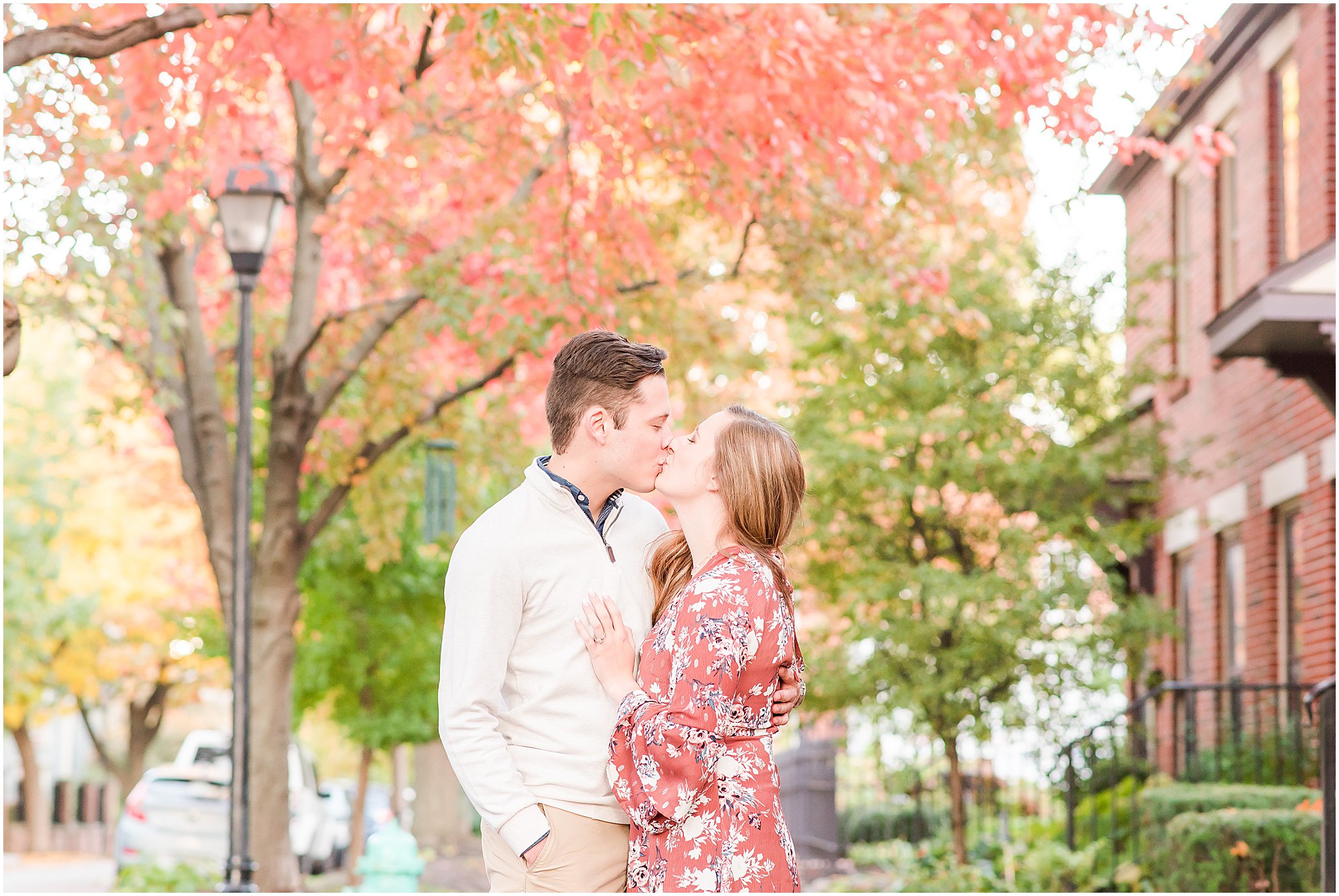 Couple kissing in front of red trees during Lockerbie Square engagement session