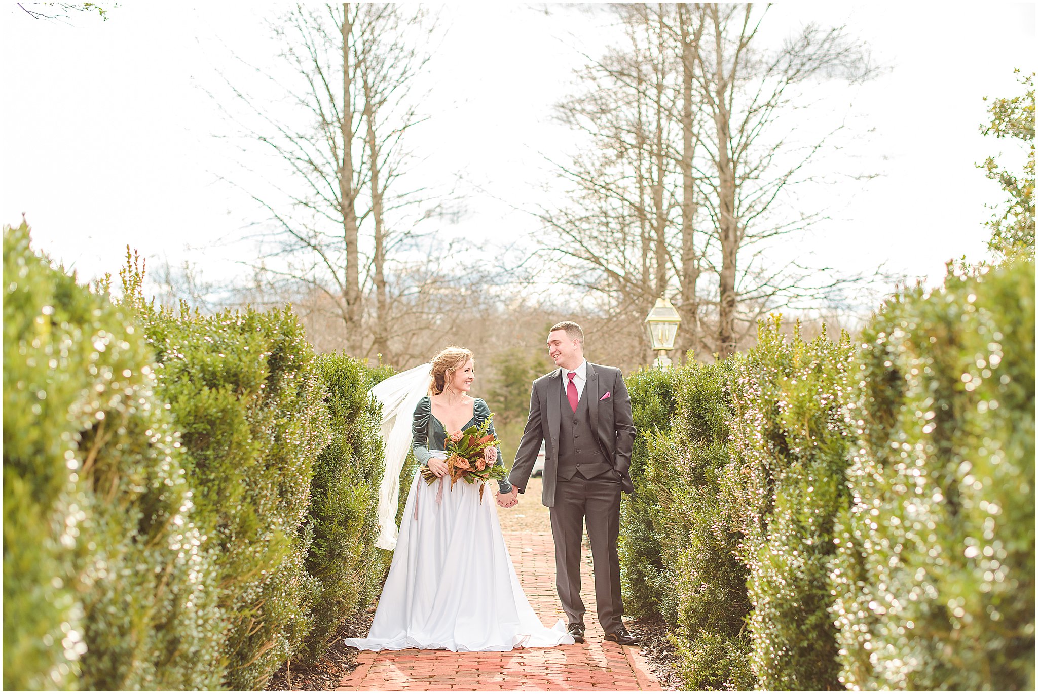 Bride and groom holding hands and smiling at one another during Mount Ida Farm wedding
