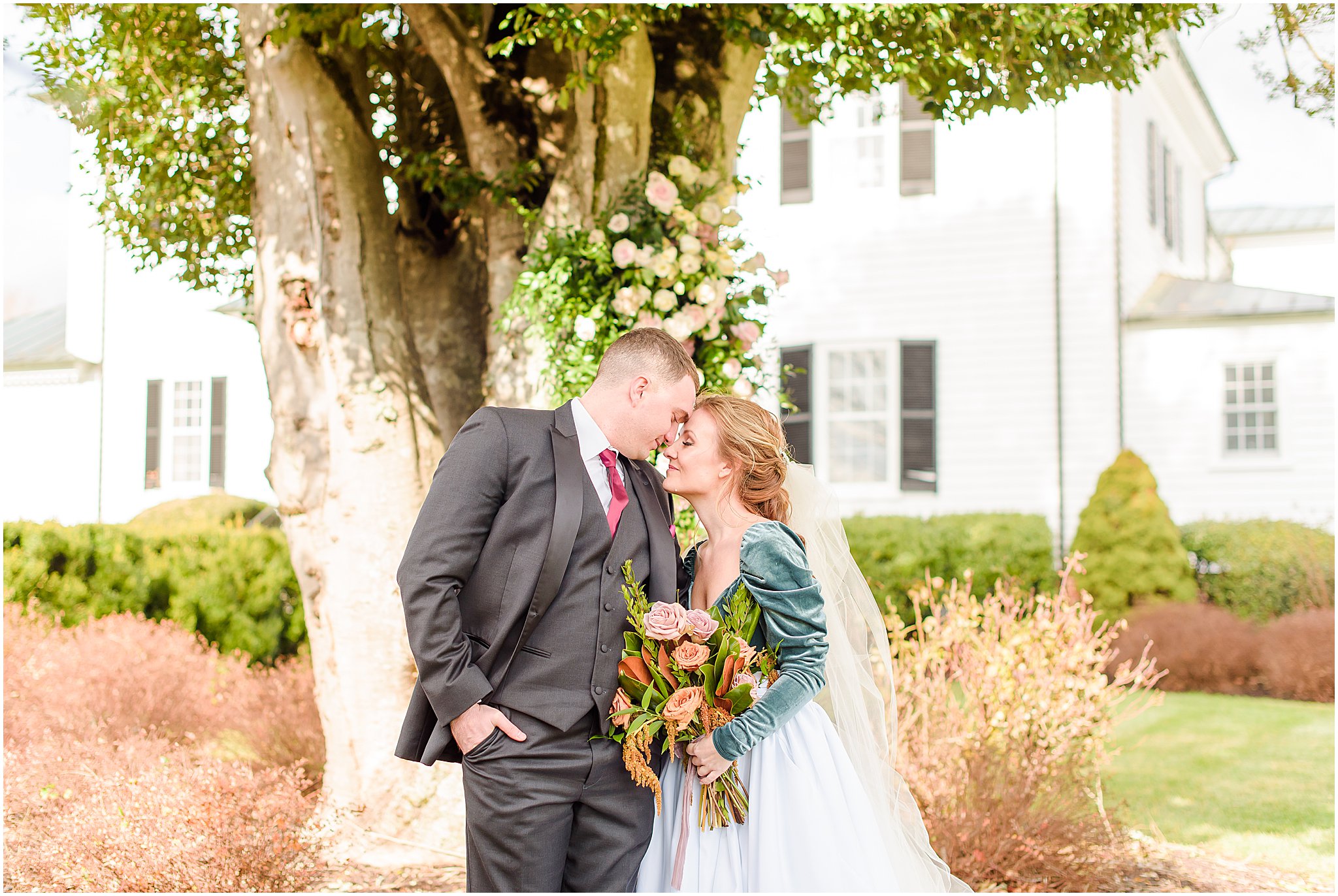 Bride and groom nose to nose in front of a floral display at ceremony site Mount Ida Farm wedding