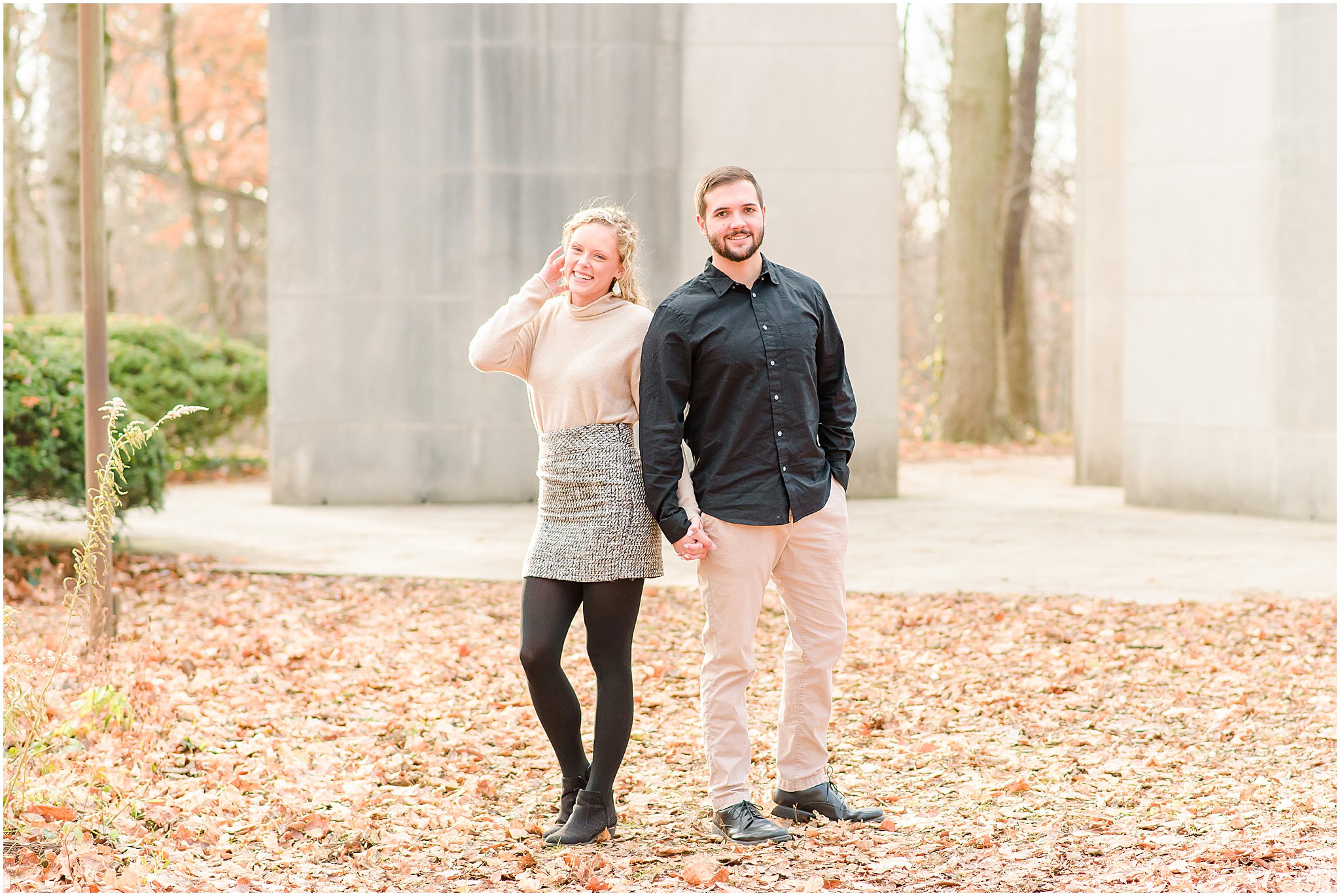 Couple holding hands and laughing towards camera during Holcomb Gardens engagement session