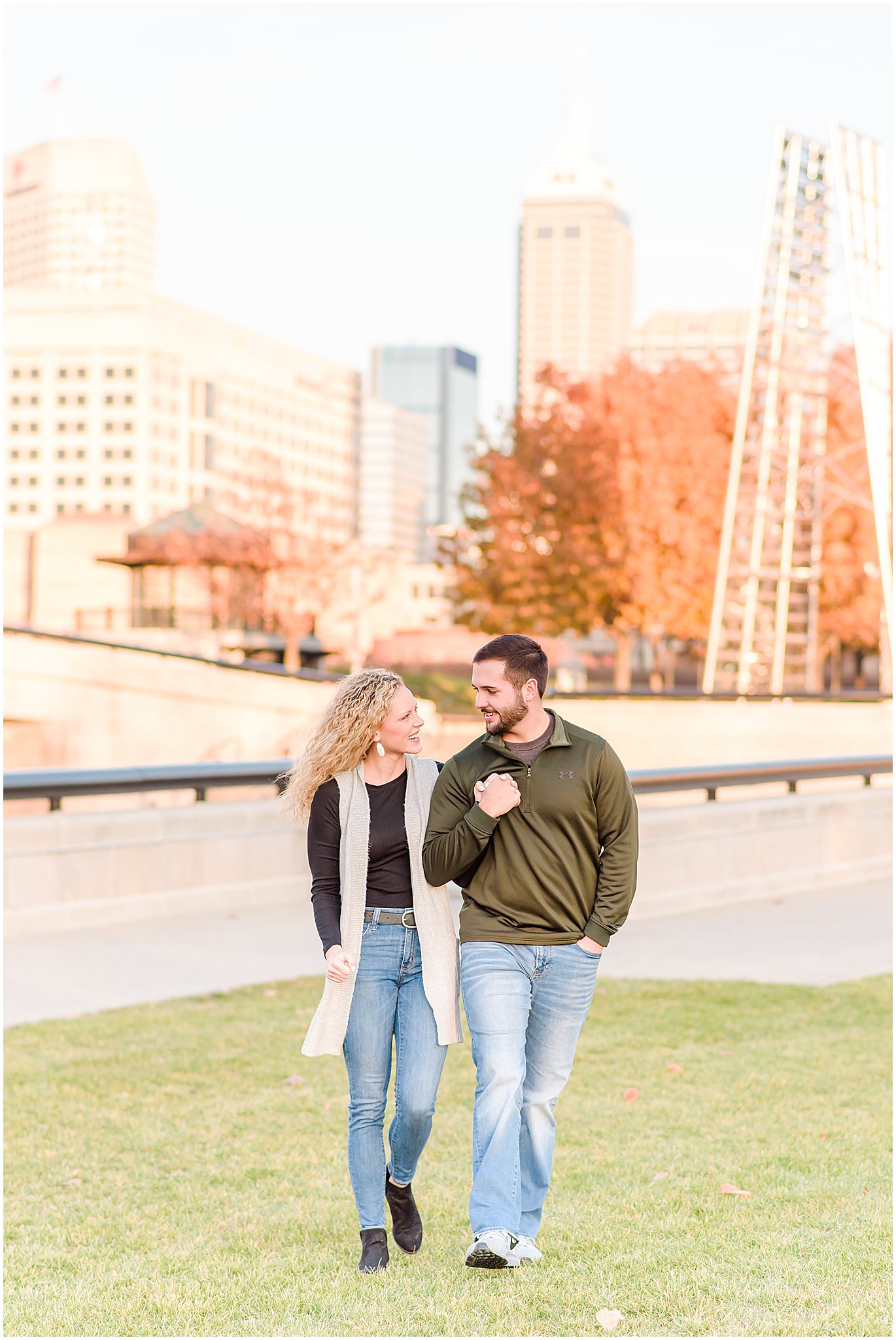 Couple holding hands and walking towards camera during Indianapolis Canal Engagement Session