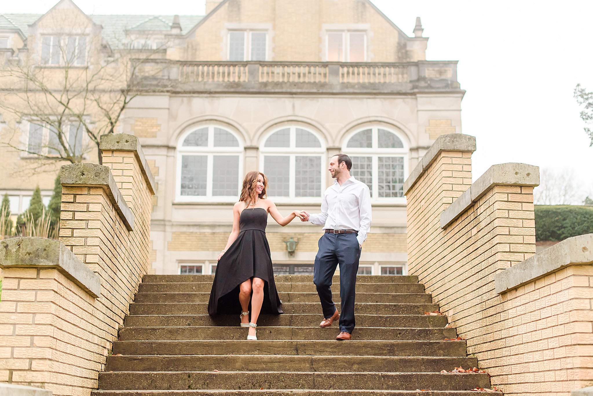 Couple holding hands and laughing walking down the stairs during Laurel Hall Engagement Session