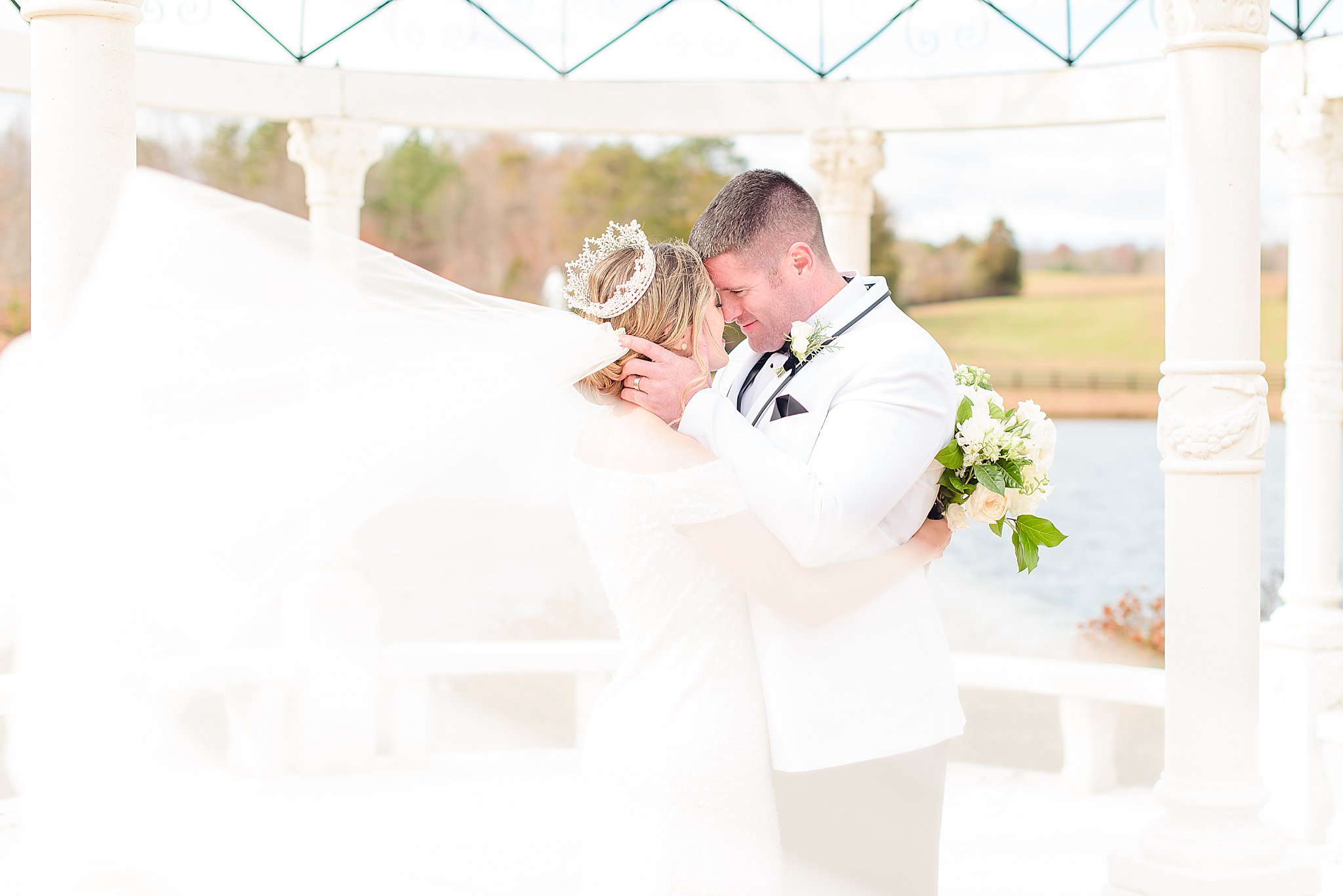 Couple nose to nose while veil swooping in the wind Mount Ida Farm wedding