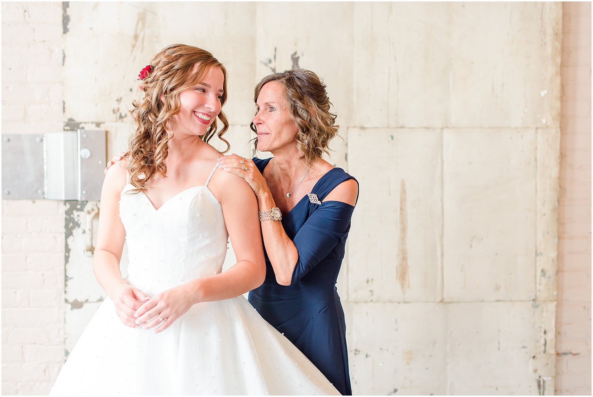 Bride smiling over shoulder at mom with tears in her eyes Coppes Commons Wedding
