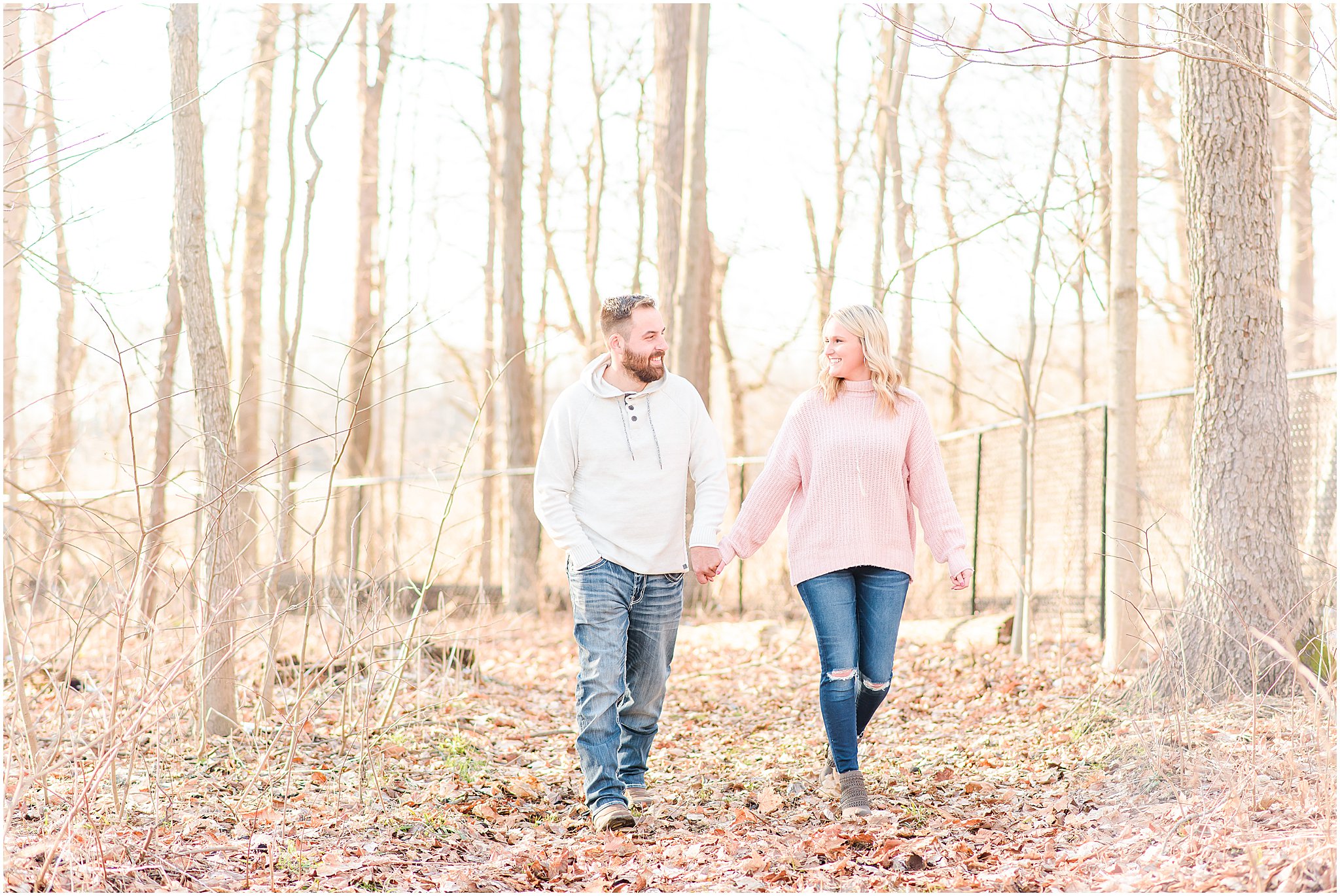 Couple smiling at each other as they hold hands and walking Lizton Lodge Engagement Session