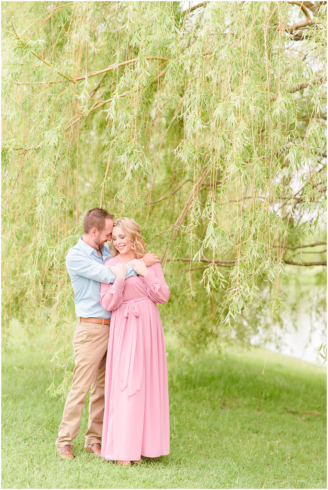 Couple nuzzling under willow tree during Coxhall Gardens engagement session