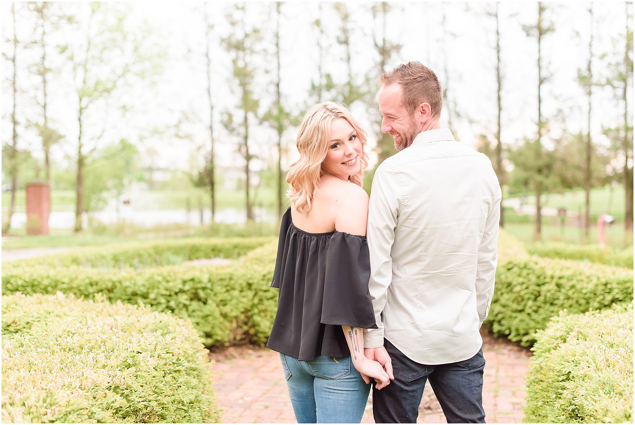Couple smiling over shoulder during Coxhall Gardens engagement session
