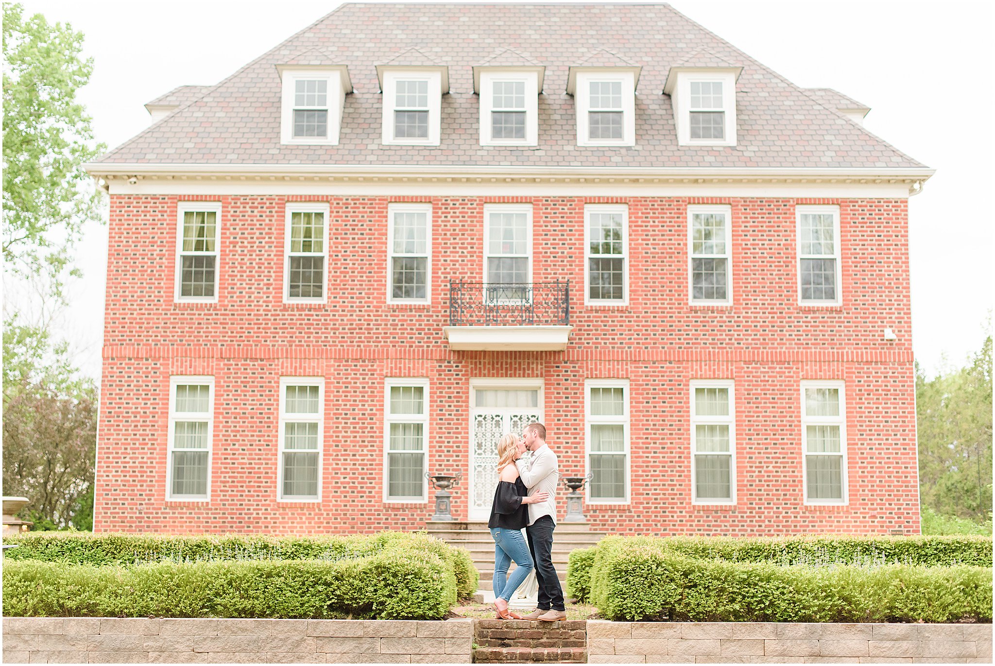 Couple kissing in front of Coxhall Mansion during Coxhall Gardens engagement session