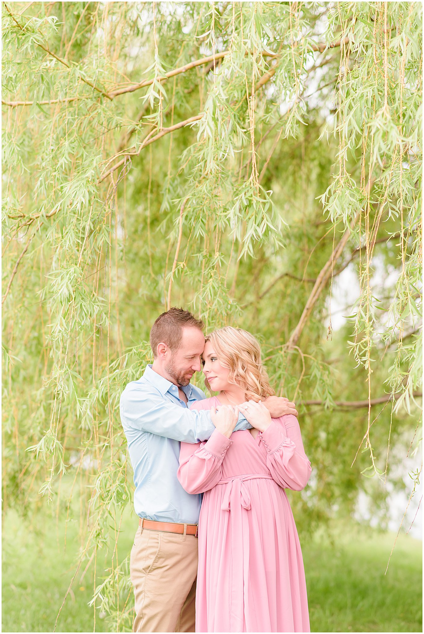 Couple nose to nose by willow tree during Coxhall Gardens engagement session