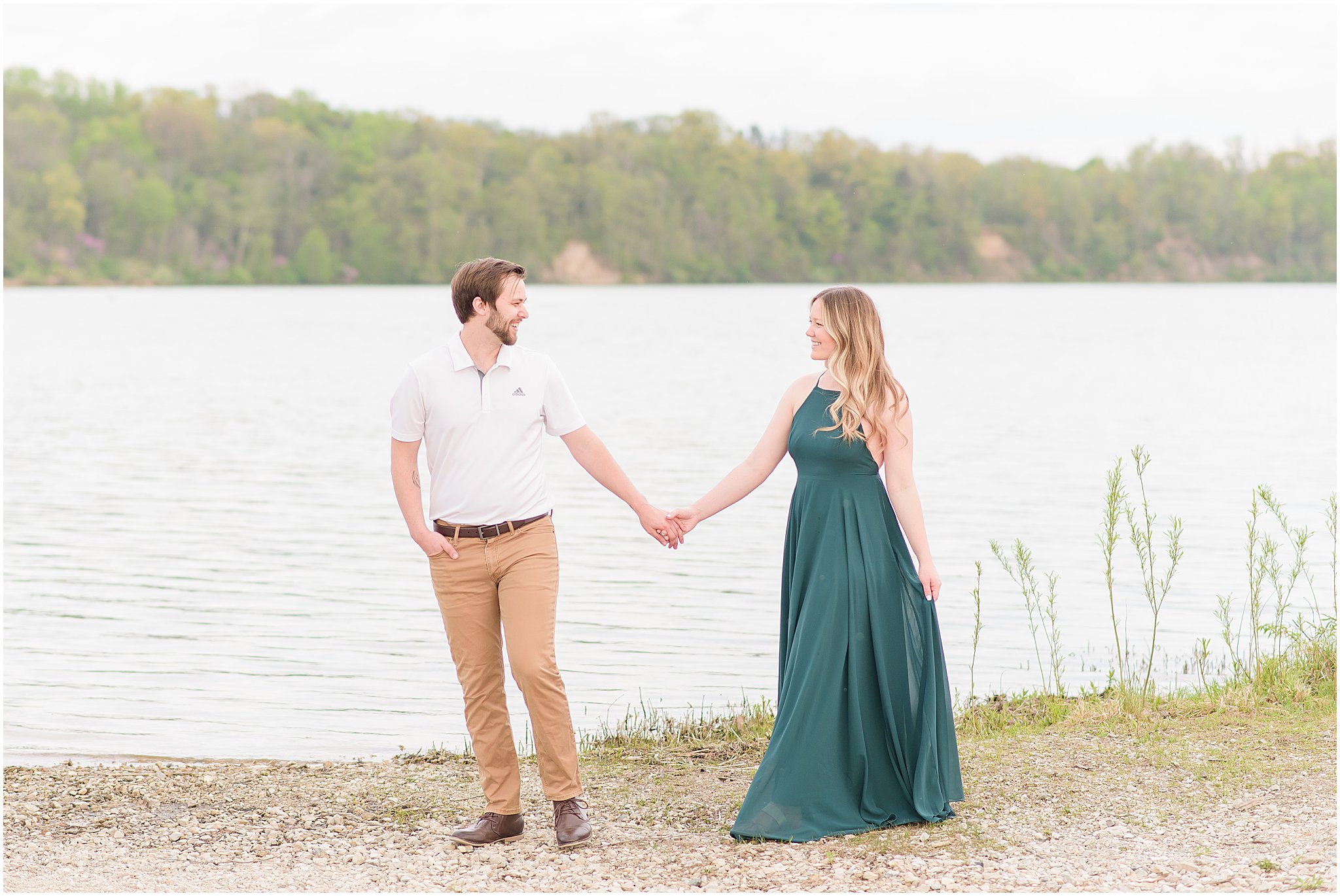 Couple holding hands and strolling along lake during Eagle Creek Park Engagement Session
