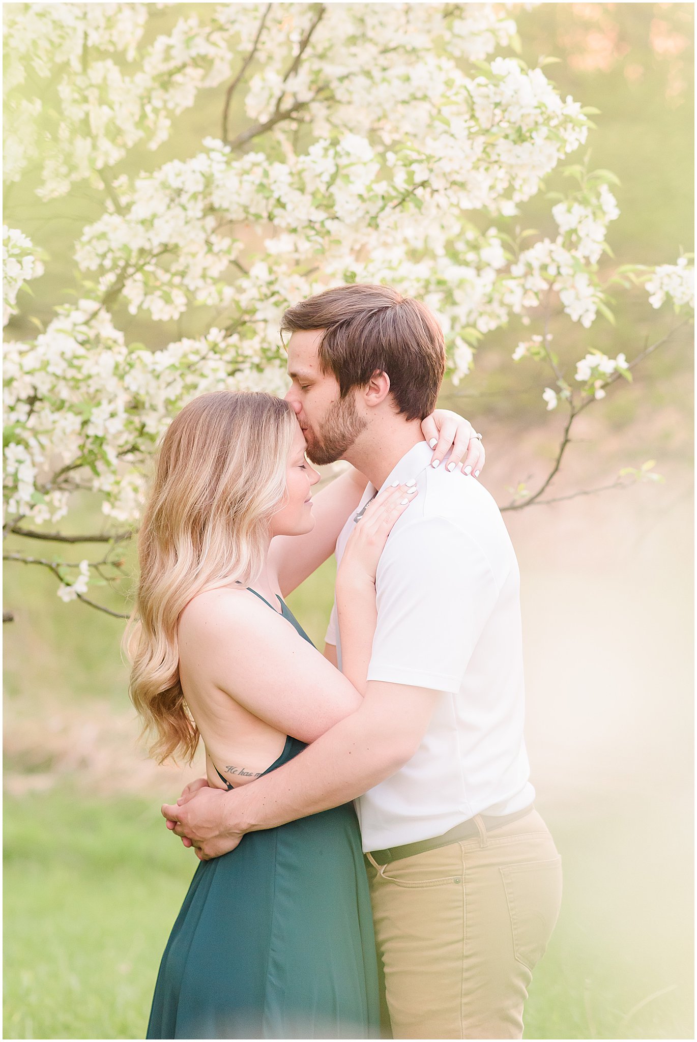 Forehead kiss in front of spring tree during Eagle Creek Park Engagement Session