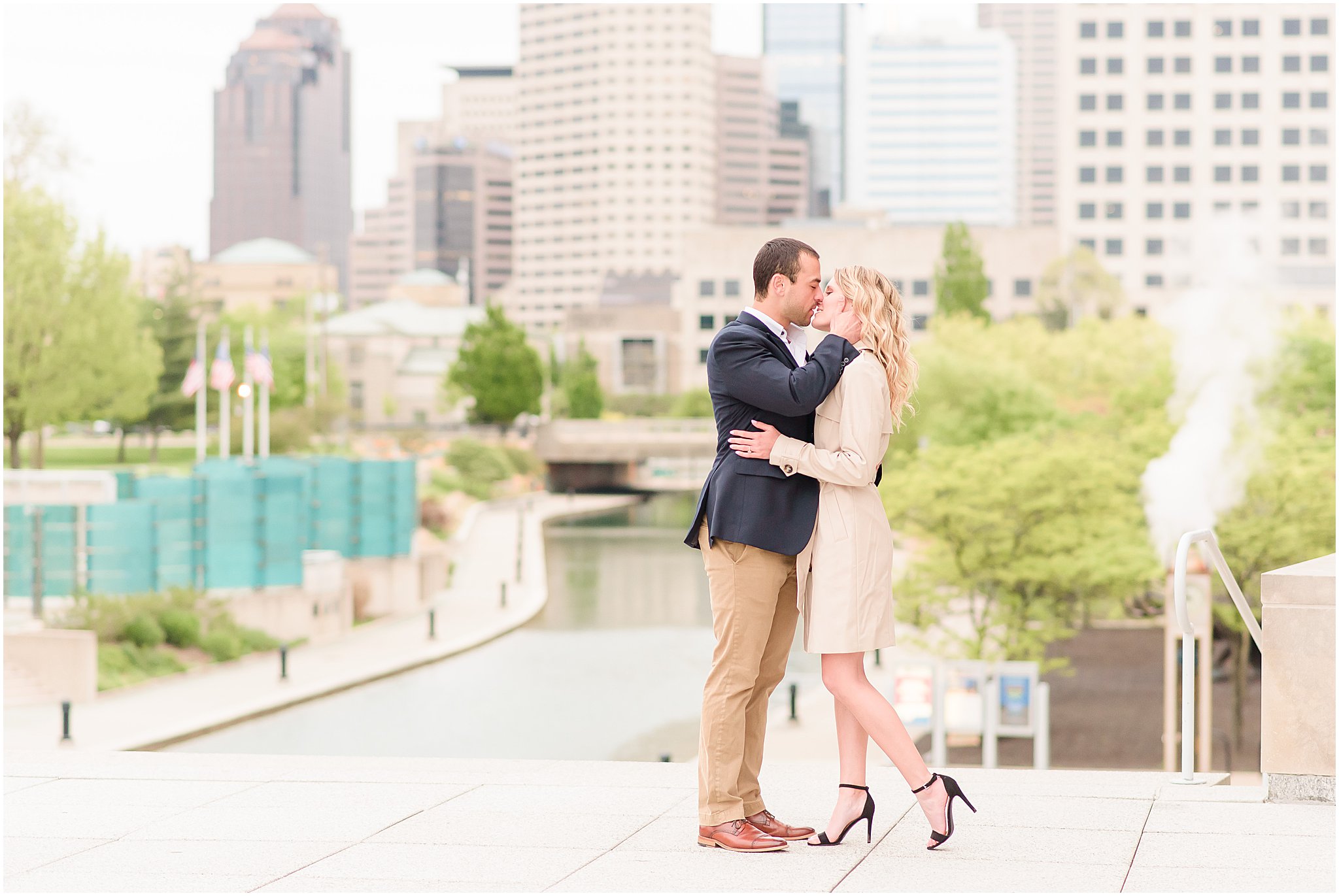 Couple kissing in front of Indy skyline during Indianapolis Canal engagement session 