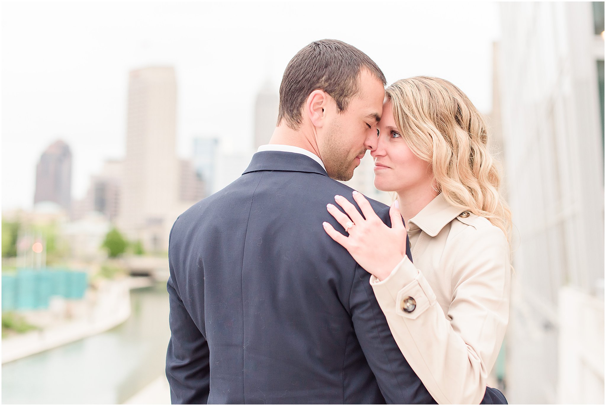 Couple nose to nose in front of Indy skyline during Indianapolis Canal engagement session 