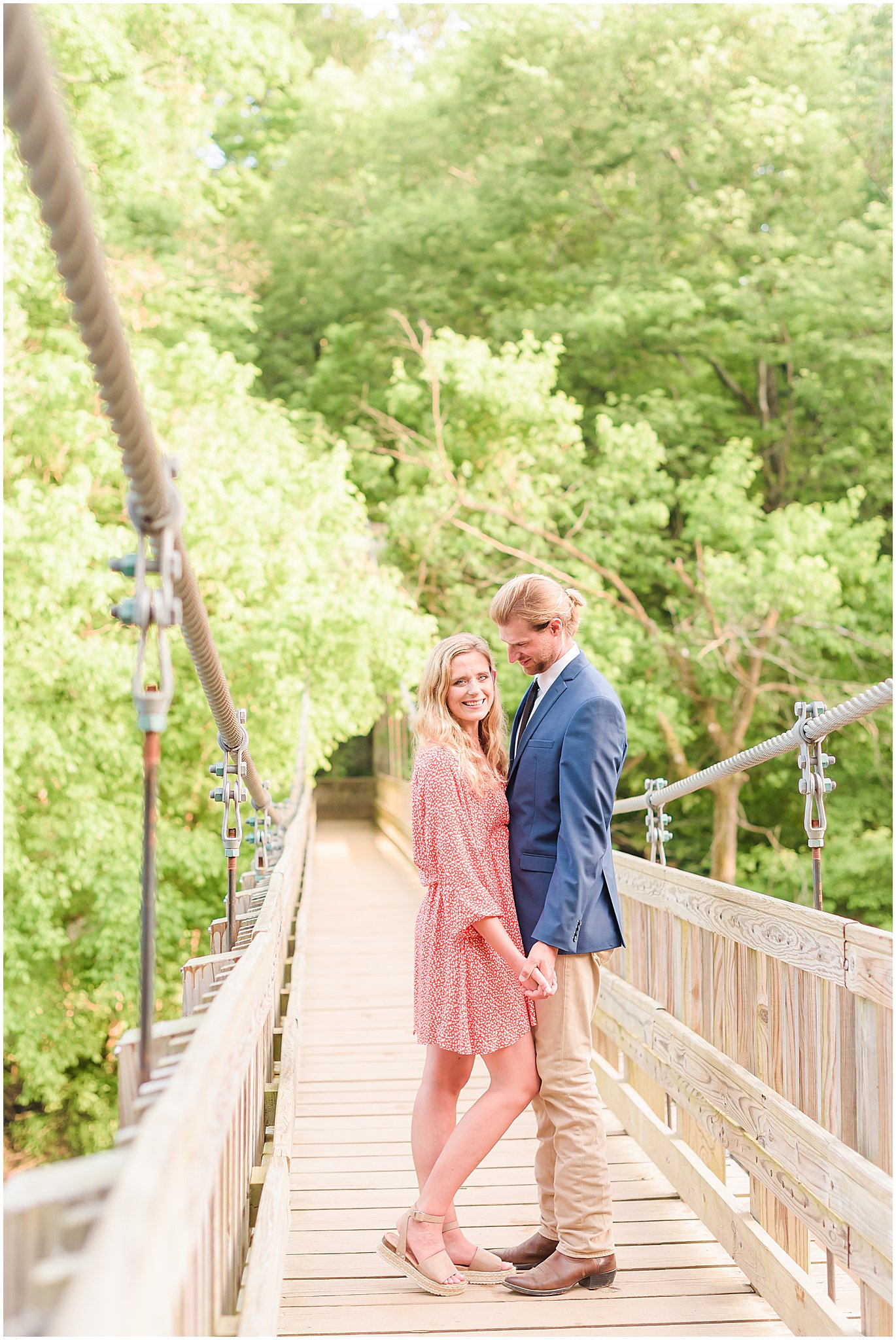 Couple smiling and holding hands on bridge during Turkey Run State Park engagement session
