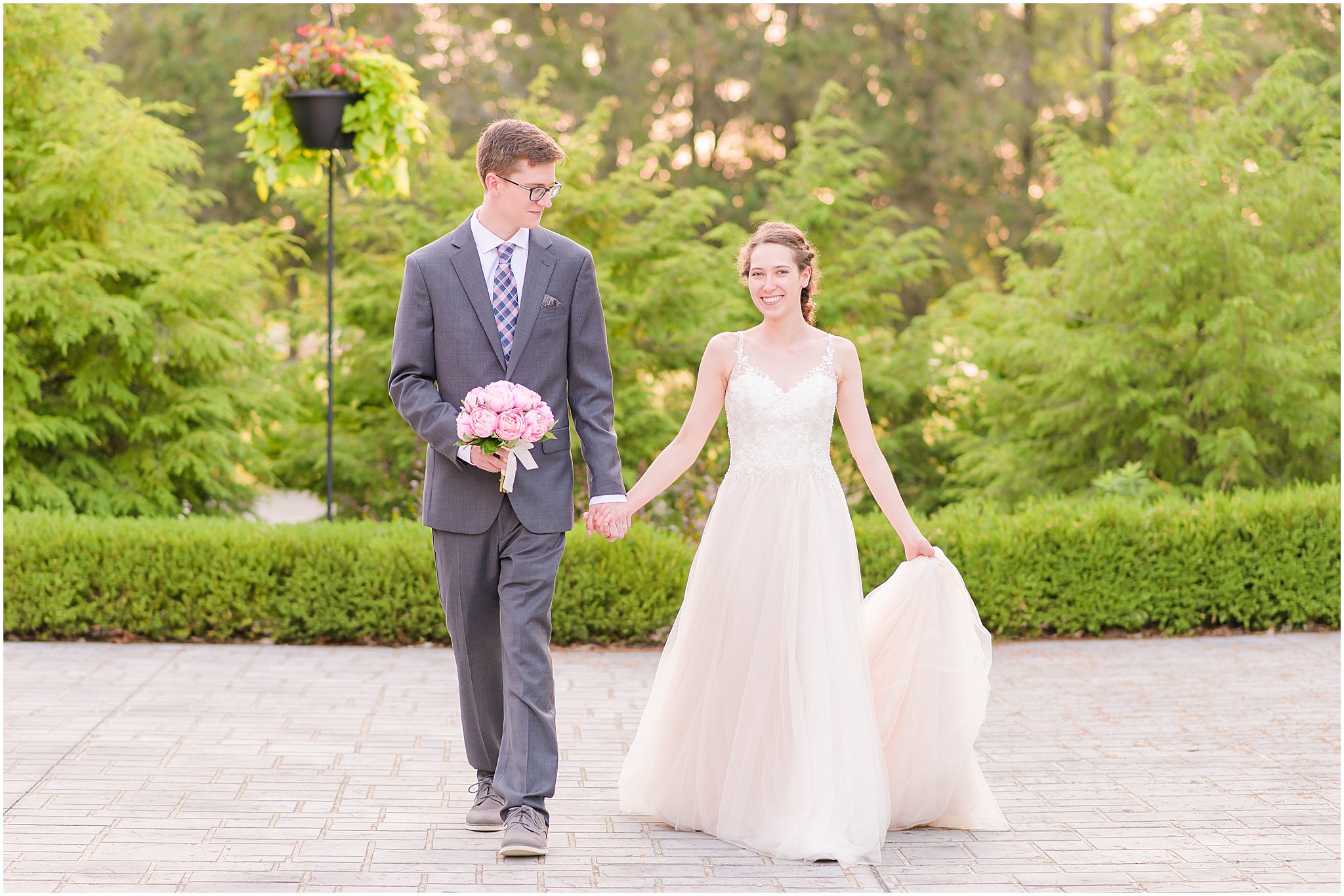 Bride and groom holding hands and walking during Coxhall Gardens wedding