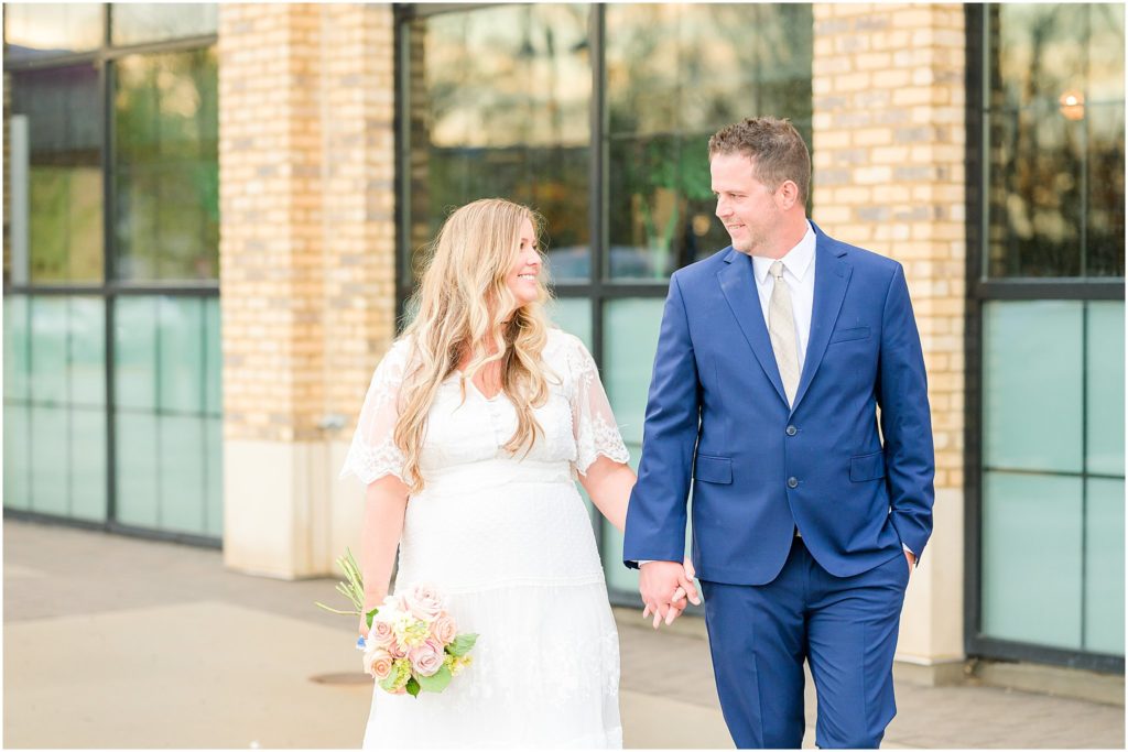 Bride and groom holding hands and walking Ironworks Hotel Elopement
