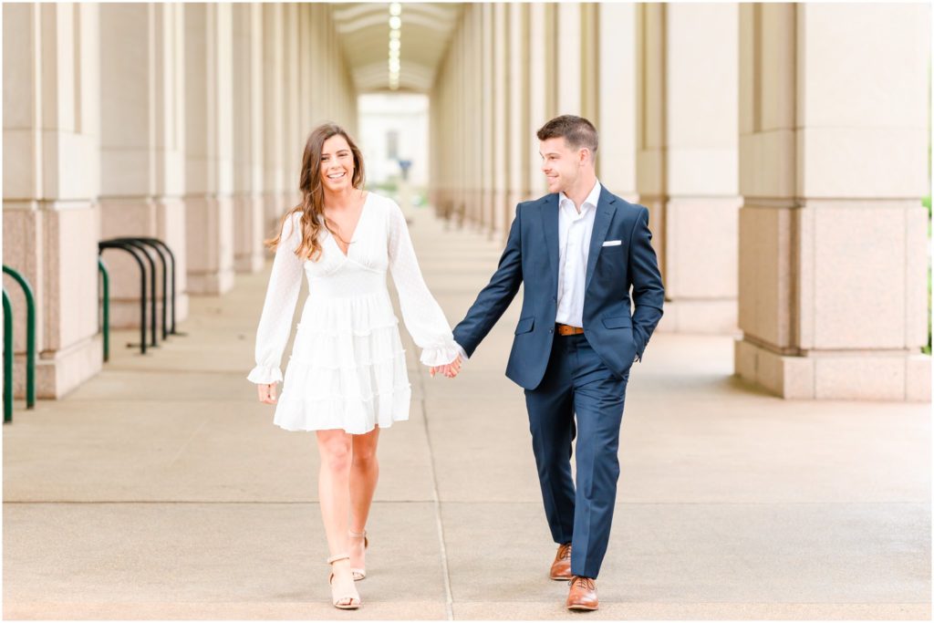 Couple walking, holding hands, and laughing downtown Indianapolis canal engagement session