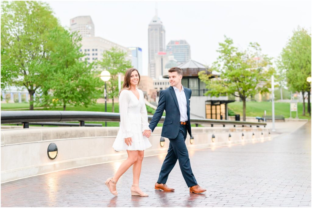 Couple walking with Indy skyline in the background downtown Indianapolis canal engagement session