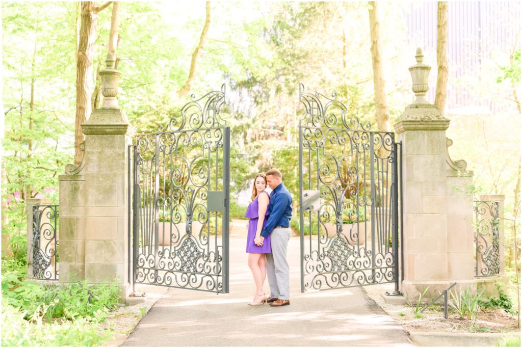 Couple nuzzling in front of ornate gate Newfields engagement session