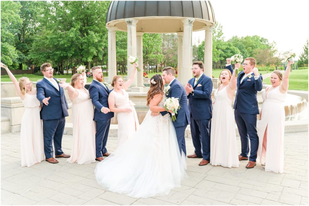 Bridal party cheering as bride and groom kiss Coxhall Gardens summer wedding