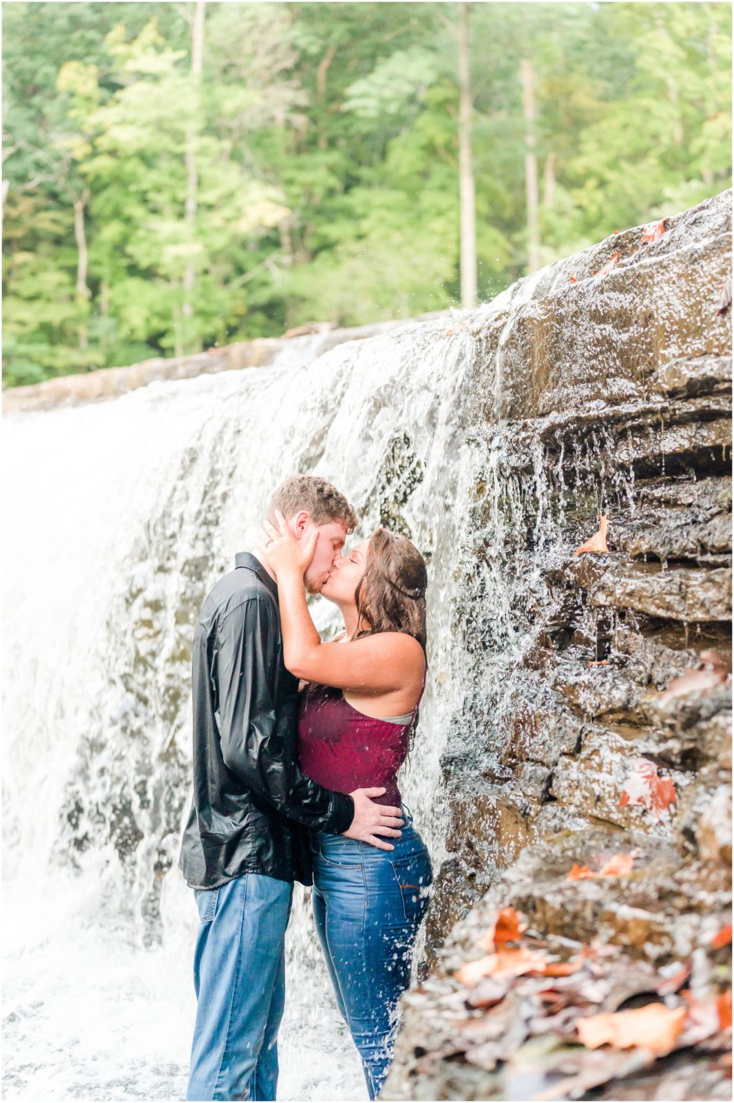 Couple kissing under waterfall Cataract Falls engagement session