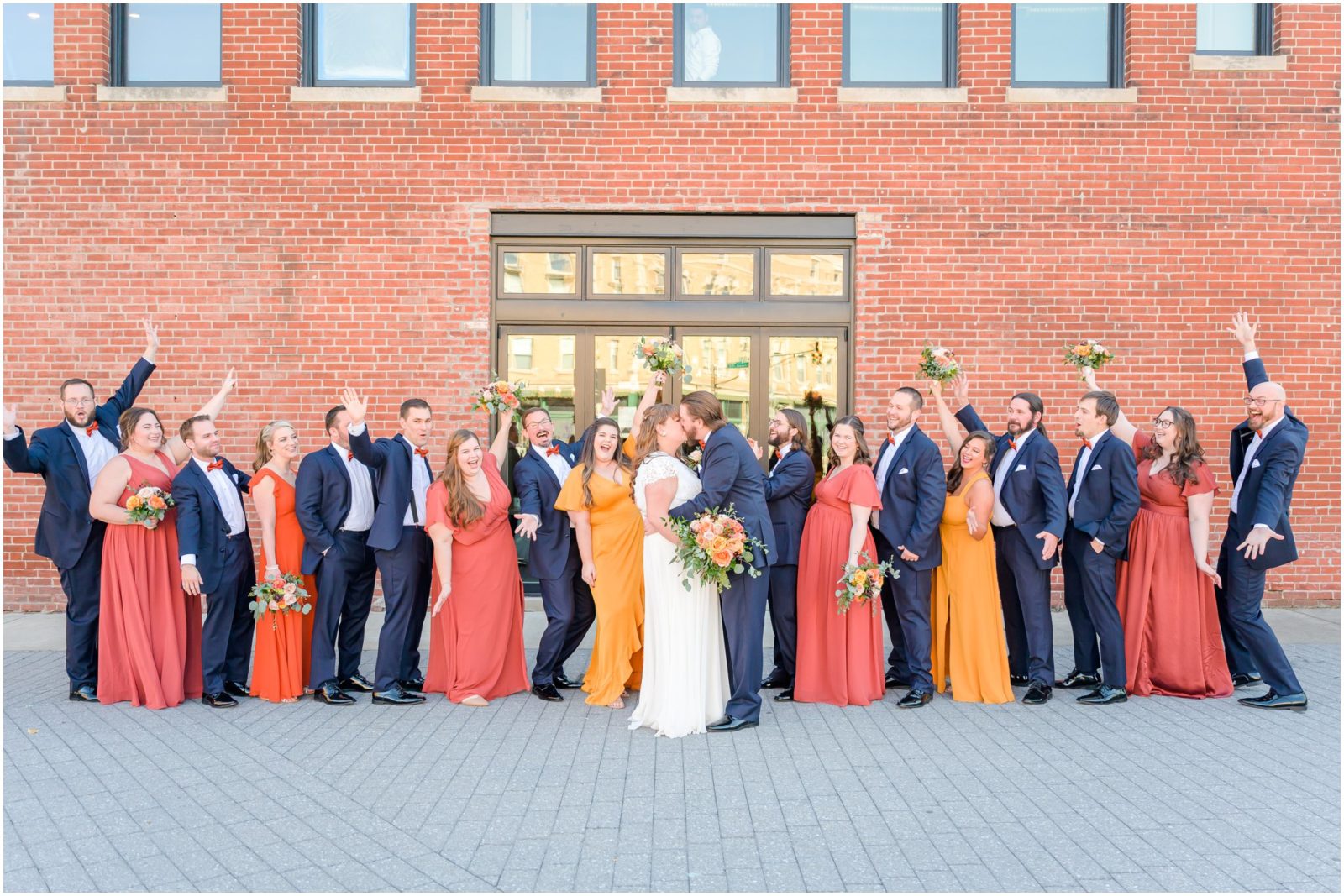 Dip kiss with bridal party cheering Fountain Square Theatre wedding