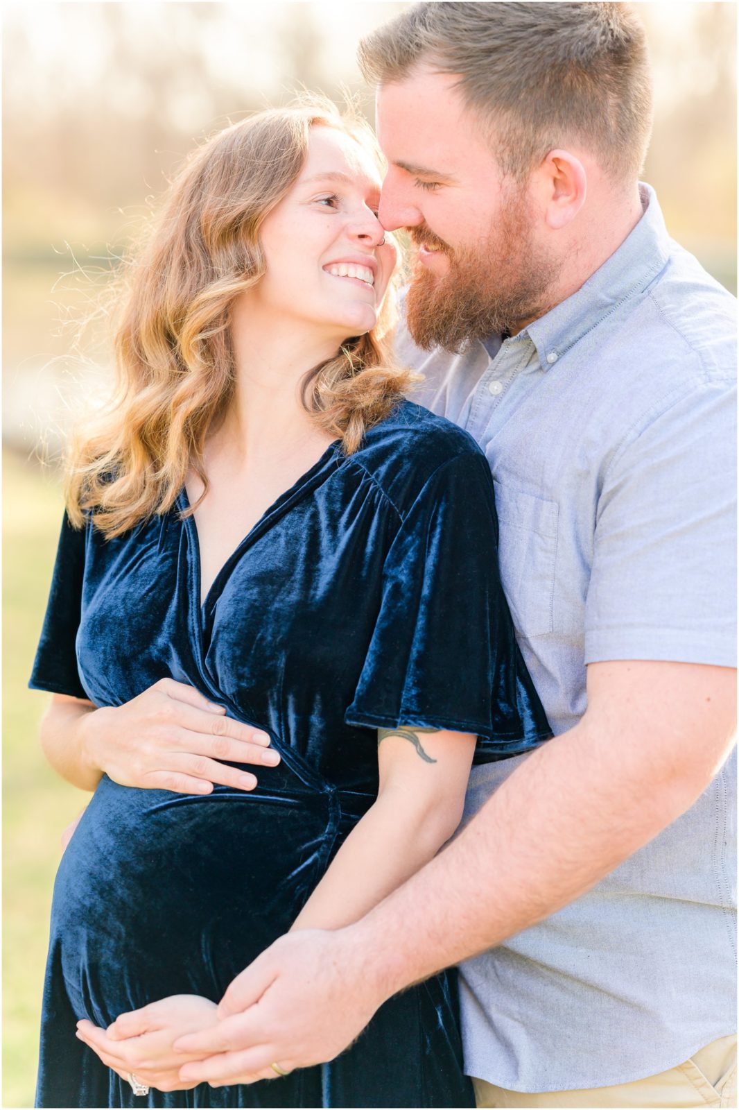 Husband and wife holding baby bump and nuzzling Holcomb Gardens maternity session