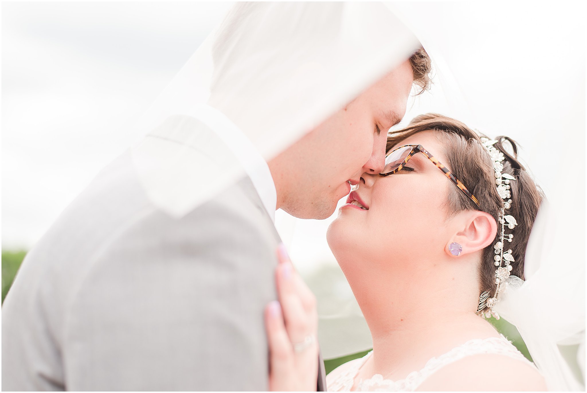 Bride and groom kissing under their wedding veil 