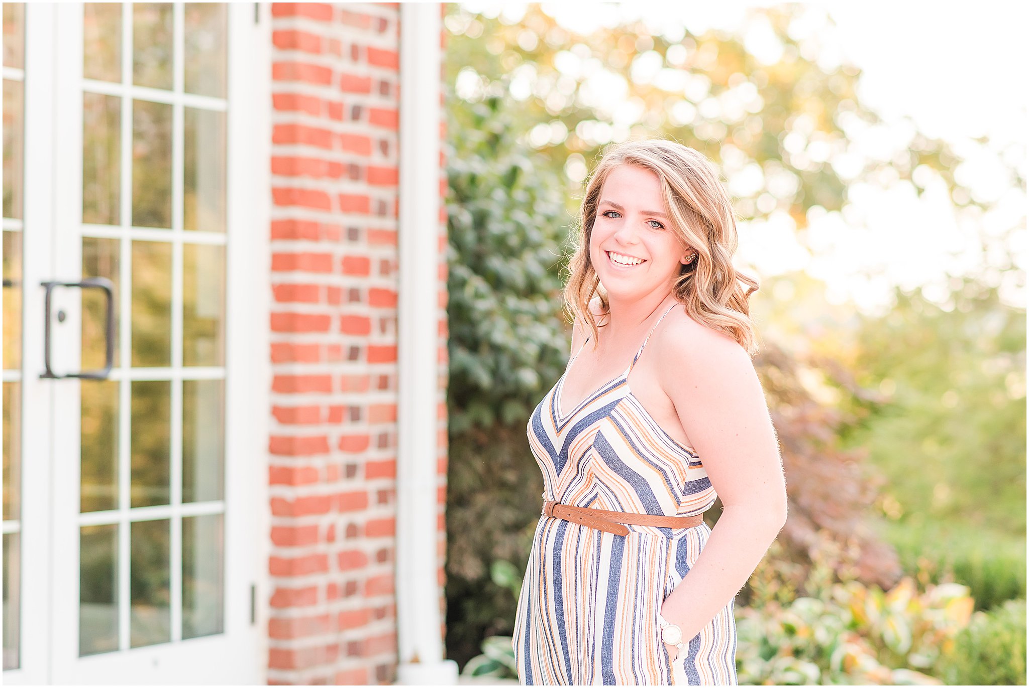 Girl in striped romper smiling at camera during Coxhall Gardens senior session
