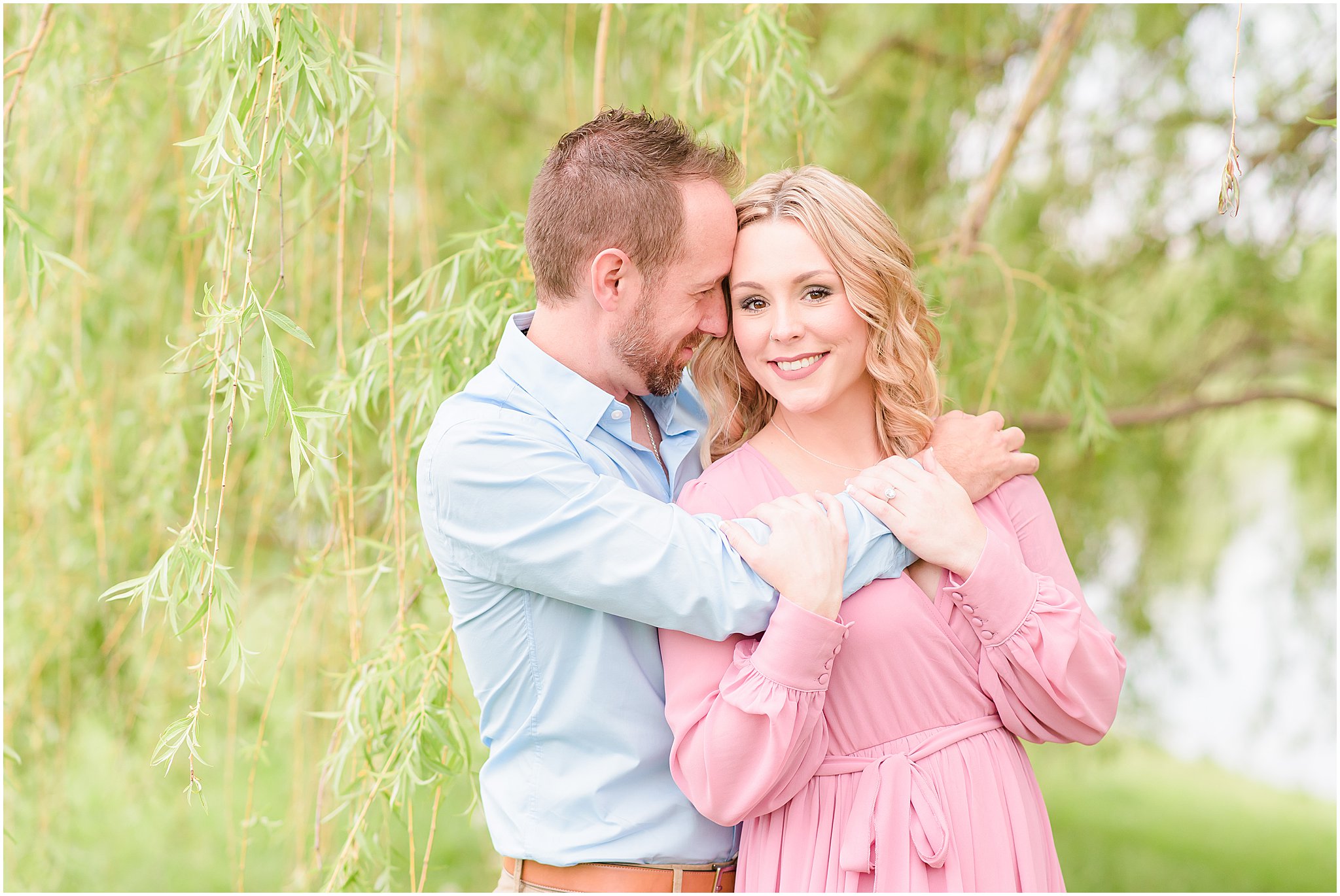 Couple nuzzling by willow tree during Coxhall Gardens engagement session